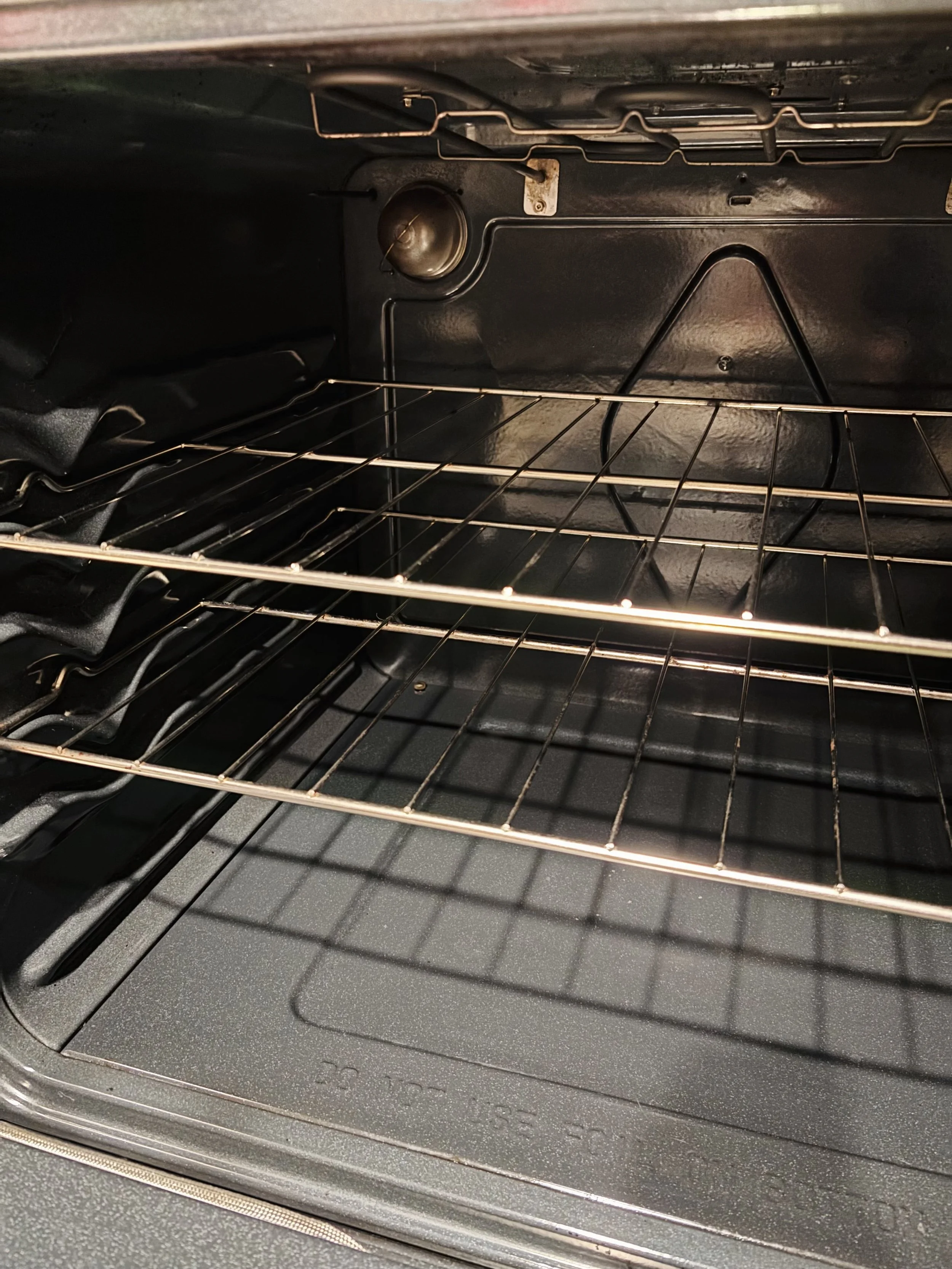 Inside of an empty oven with metal racks and a heating element at the back.