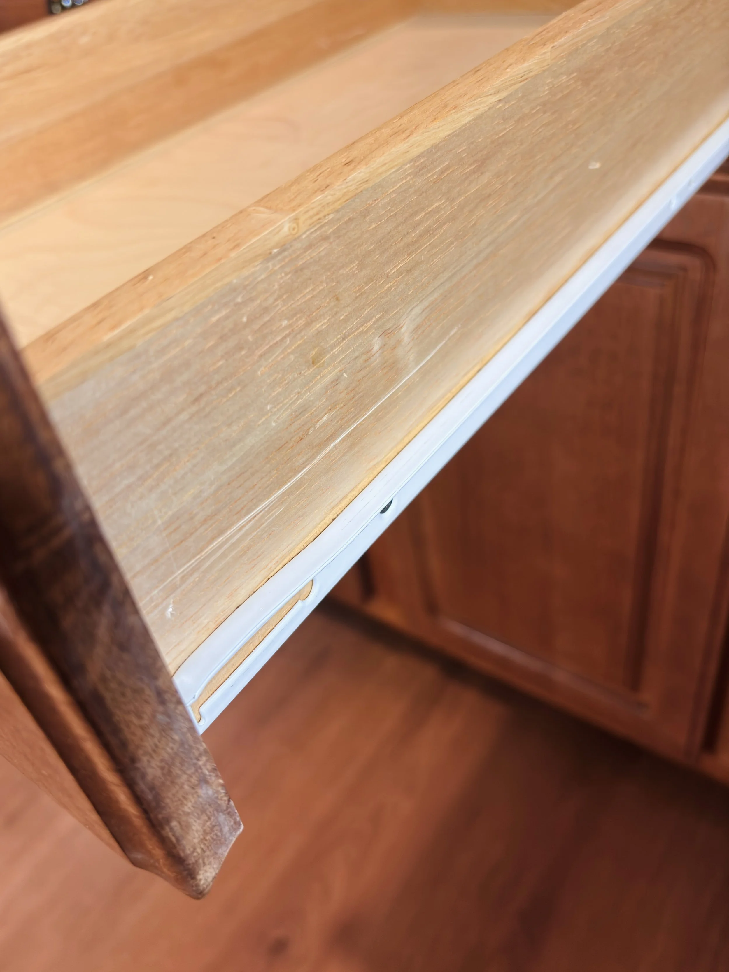 Close-up of a wooden drawer slide on a kitchen drawer, showing both the wooden and metal parts.