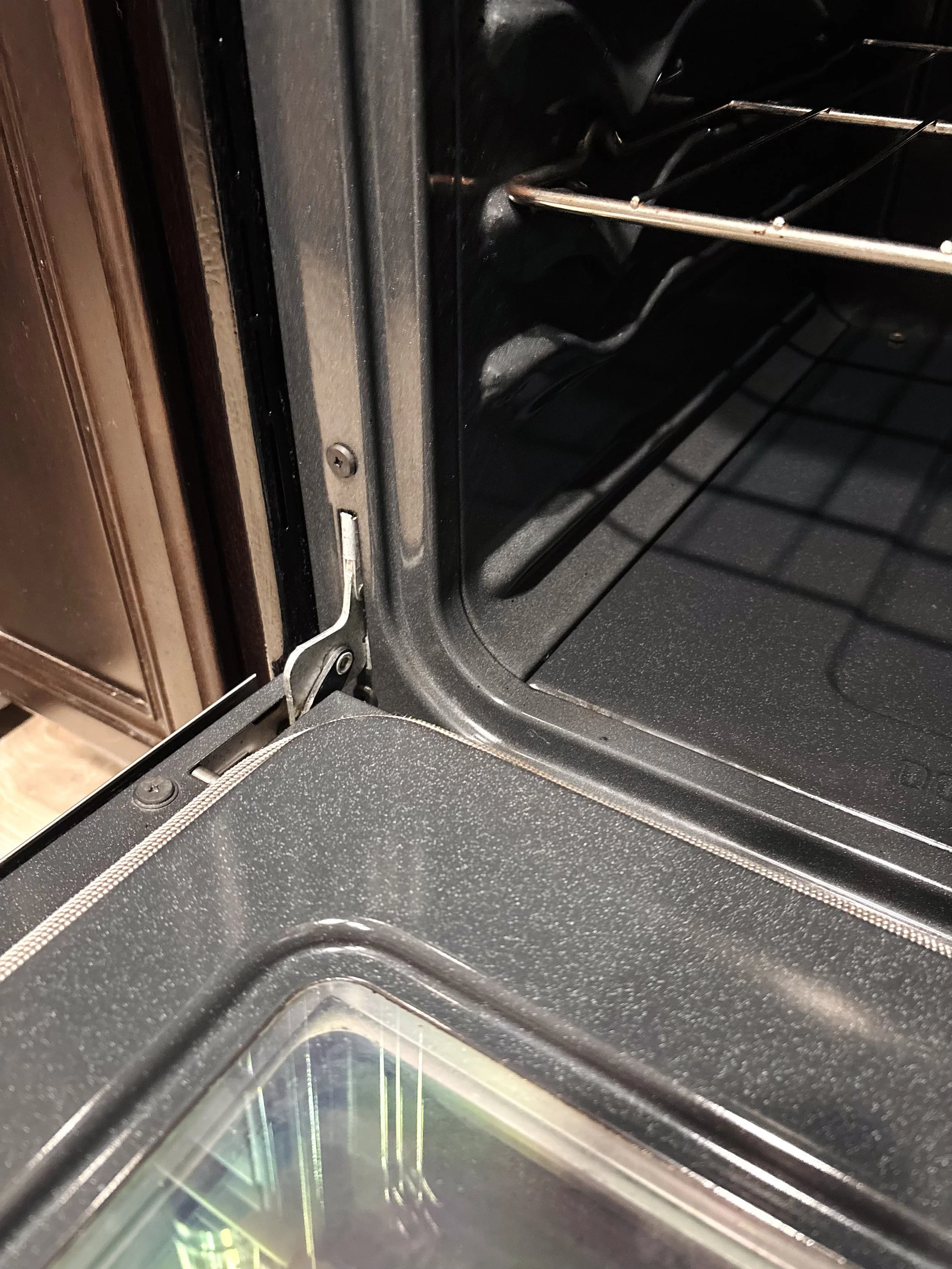Close-up of the inside of an empty black oven with oven racks and a glass door.