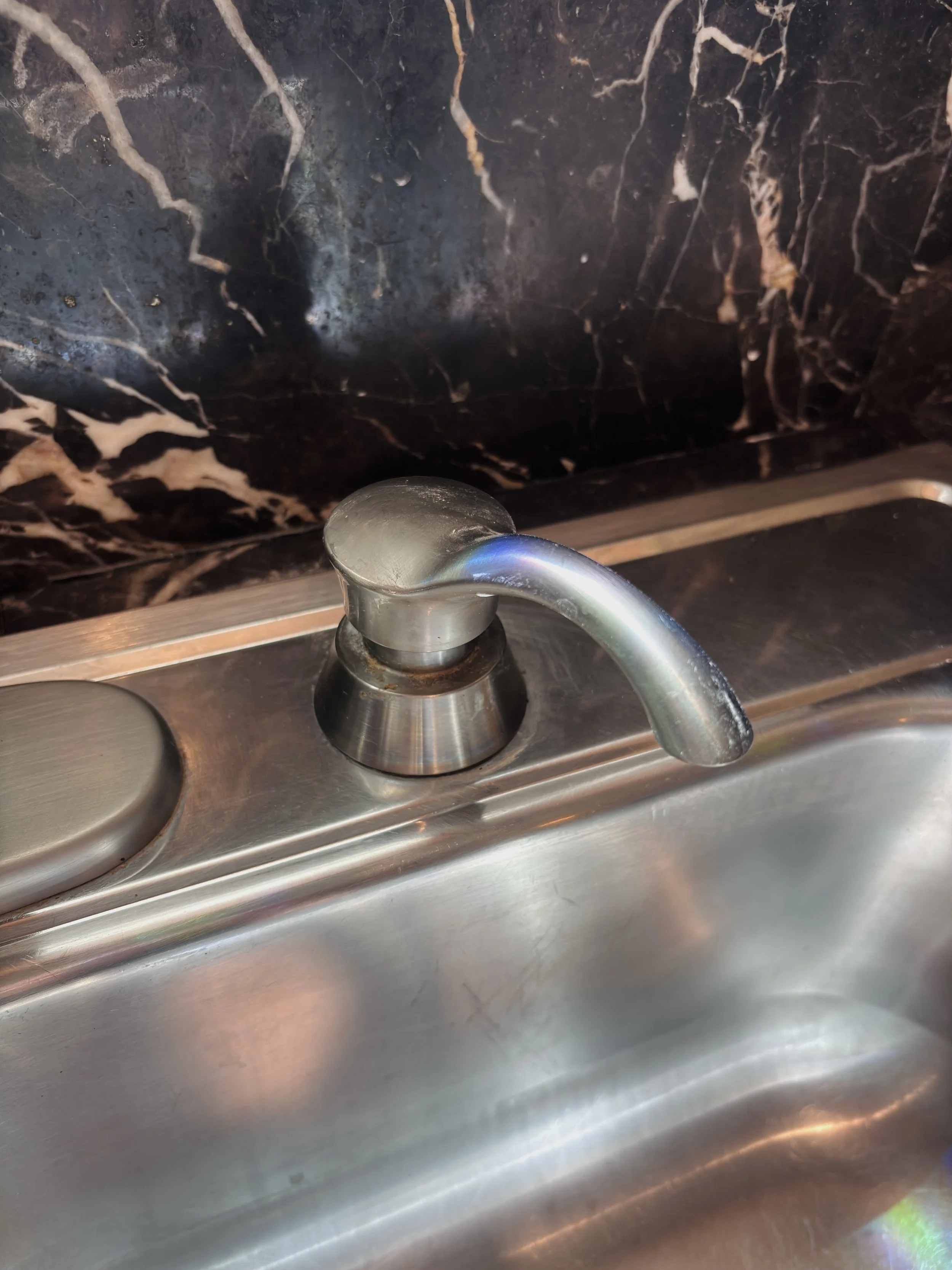 A bathroom sink with a faucet in front of a black marble backsplash.