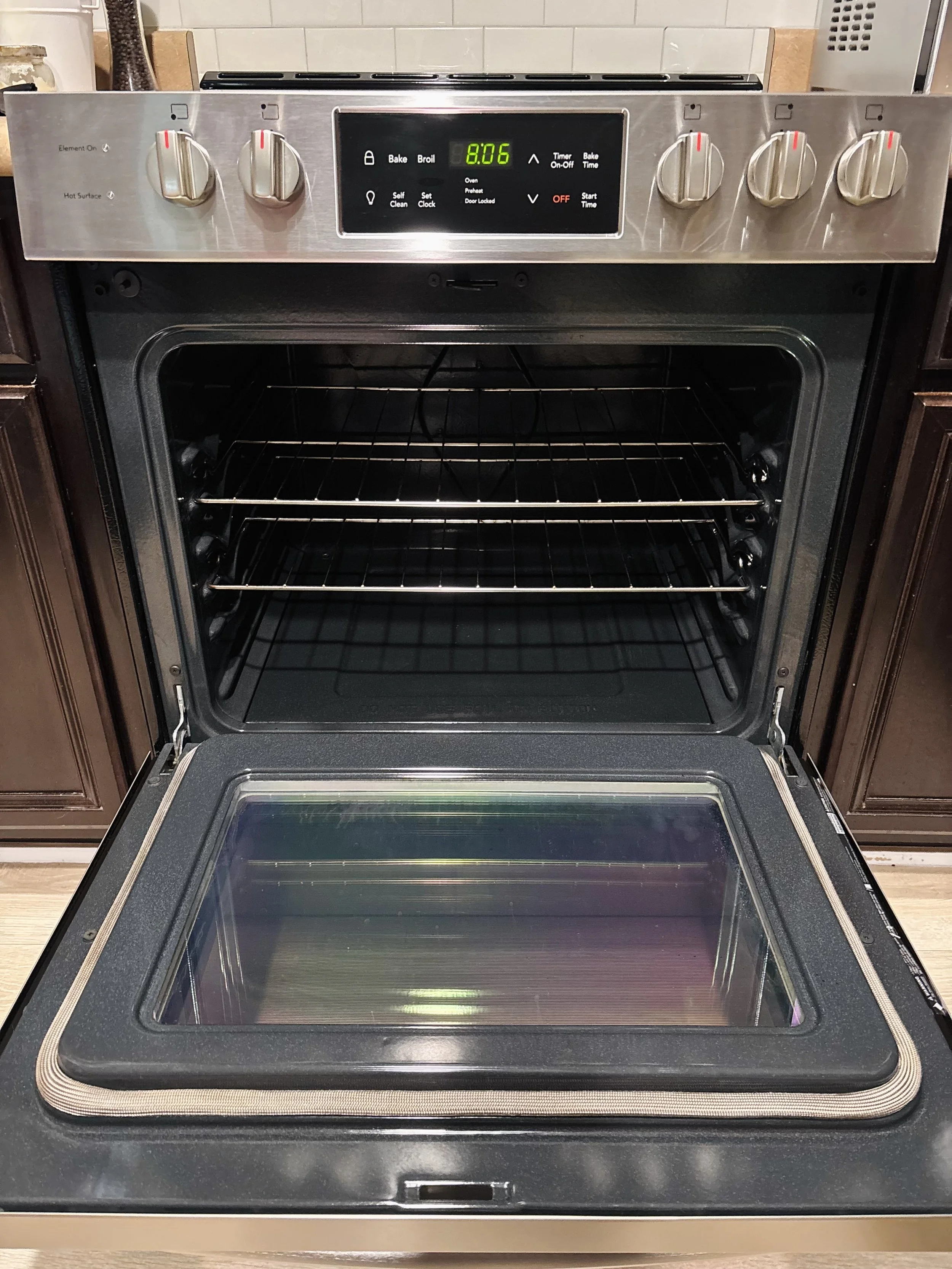 A modern kitchen oven with a digital clock displaying 8:06 and control knobs on top.