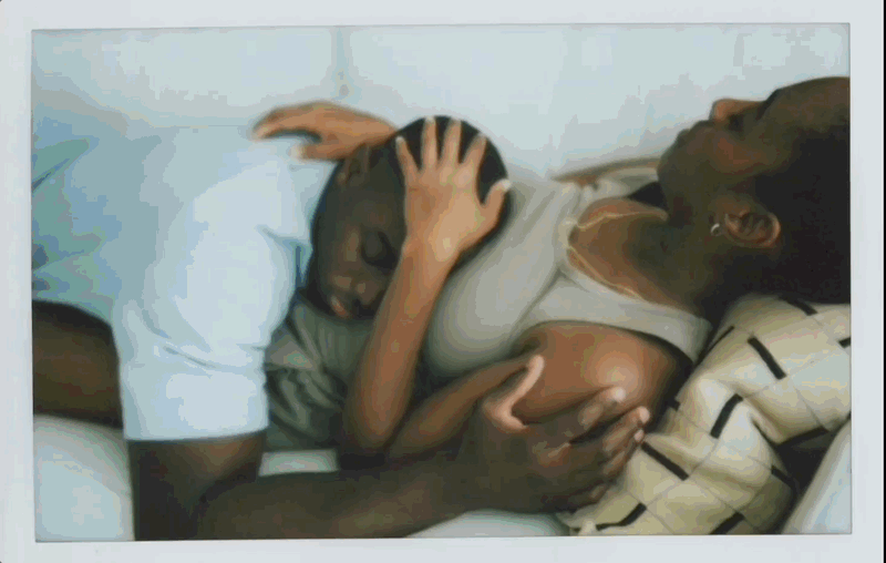 A woman lying in bed holding and comforting a child who is resting against her.