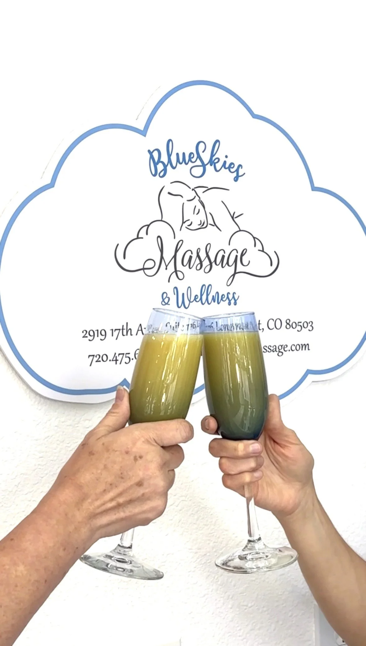 Two people clinking glasses filled with mimosa to celebrate at the Blue Skies Massage & Wellness Spa in Longmont, CO.