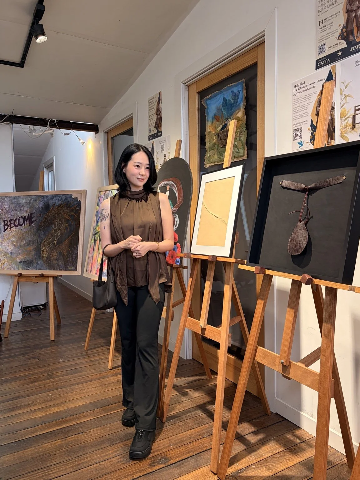 A woman standing in an art gallery surrounded by paintings and artworks, capturing a quiet creative moment connected to SERNÉ’s artistic practice.