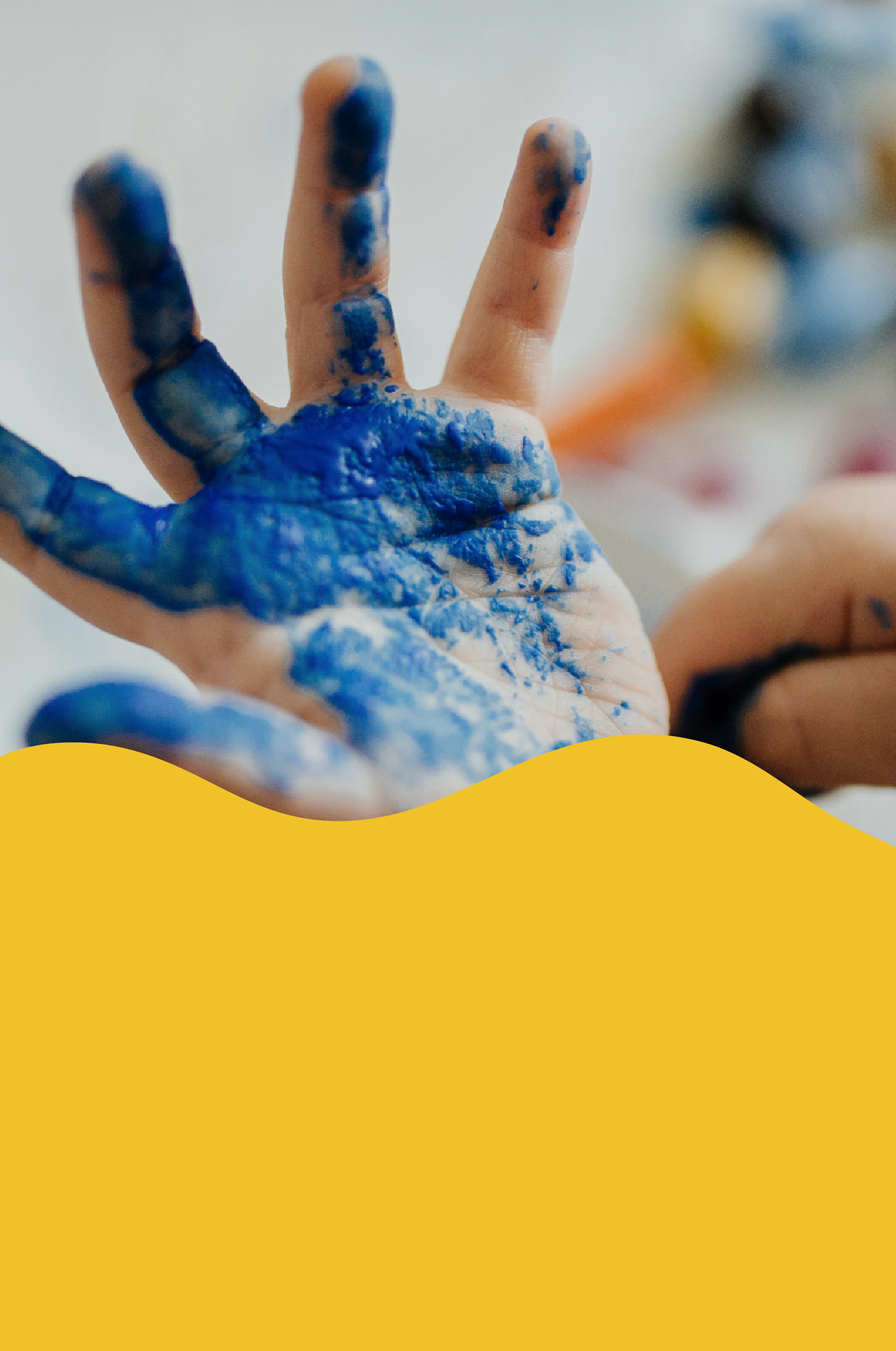 Close-up of a hand with fingers raised, covered with blue and orange paint splatters on the fingers and palm.