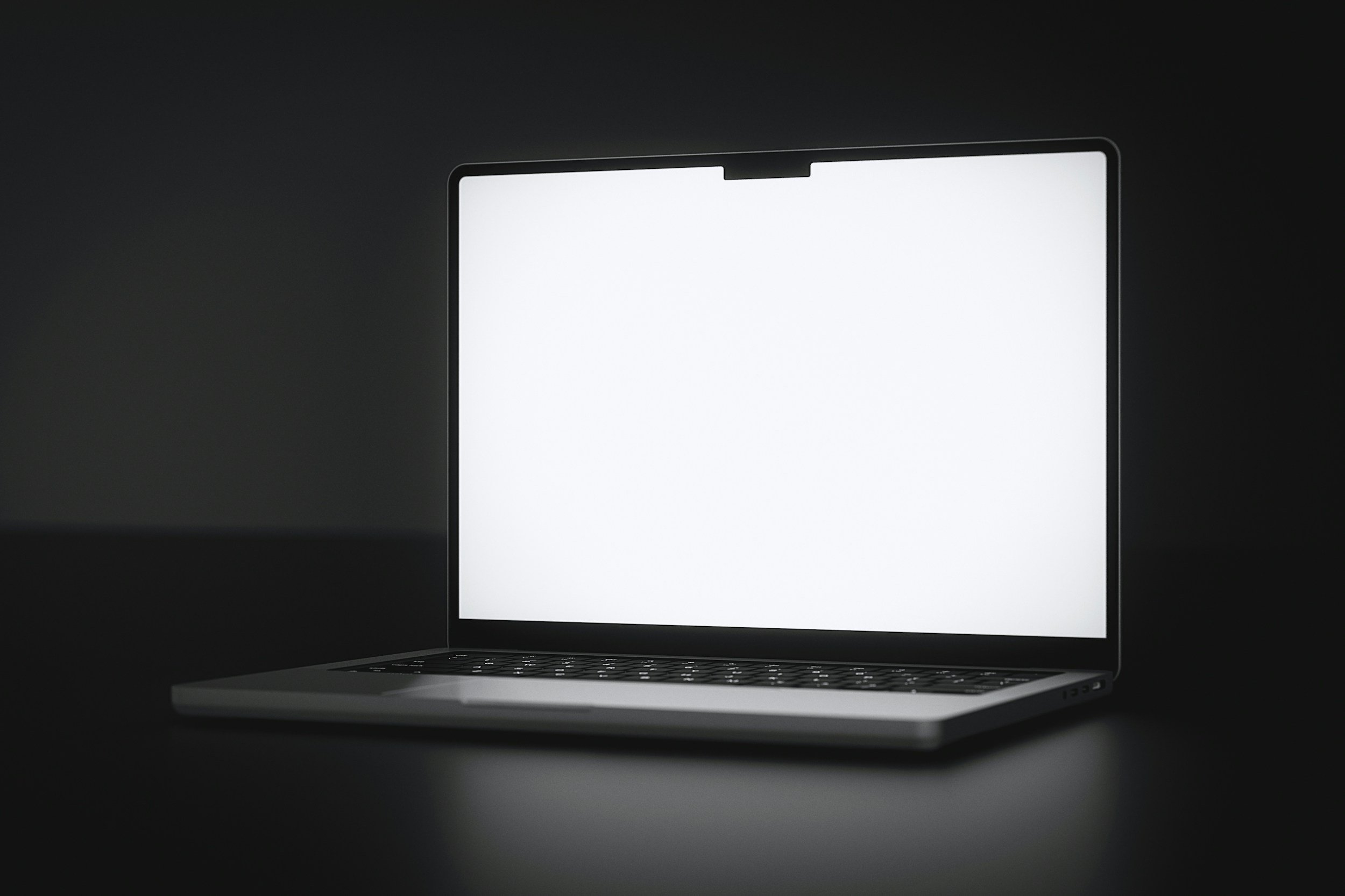Close-up of a laptop with a blank, white screen against a dark background.