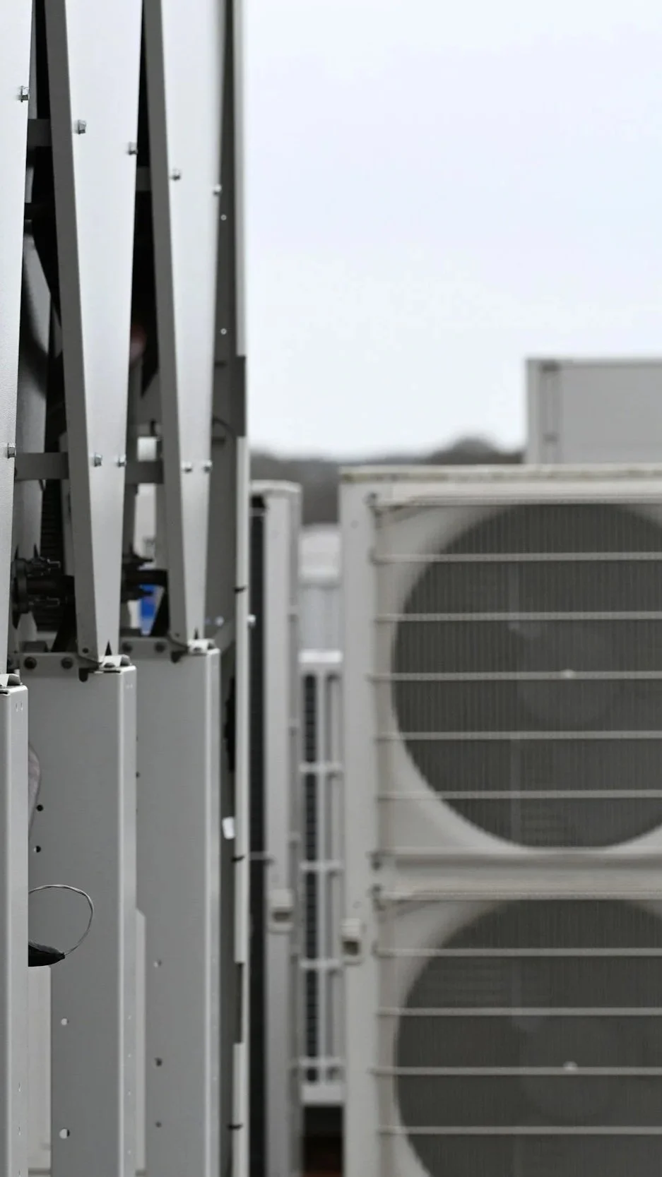 Close-up of commercial air conditioning units installed outdoors on a building rooftop, with a cloudy sky in the background.
