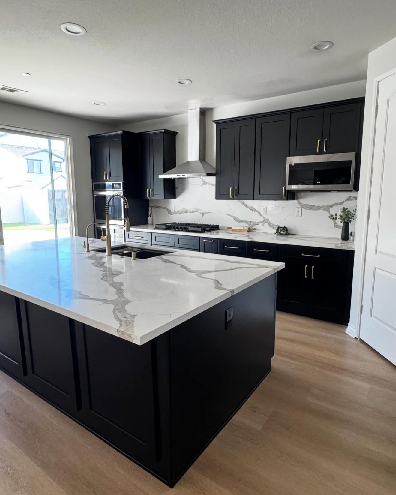 kitchen renovation completed by Skye builders construction in Waxahachie, Tx with custom black cabinetry, quartz countertops, and a large island.