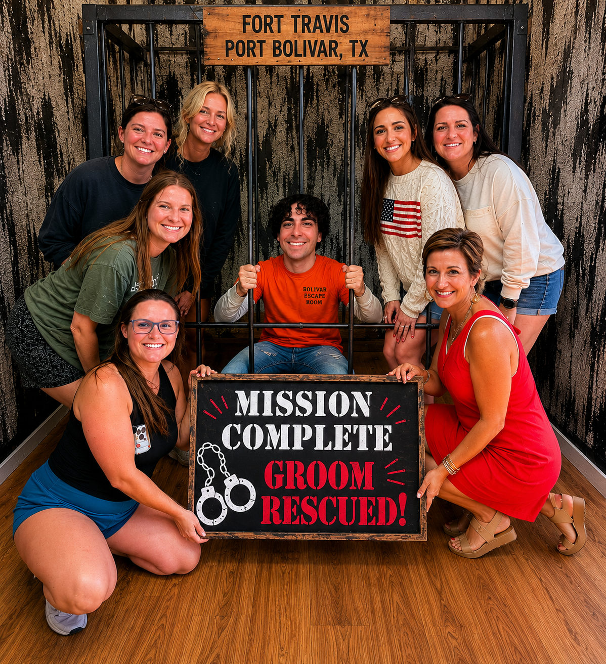 Group of friends celebrating a rescue from an escape room with a sign that reads 'Mission Complete Groom Rescued!' at Fort Travis in Port Bolivar, TX.