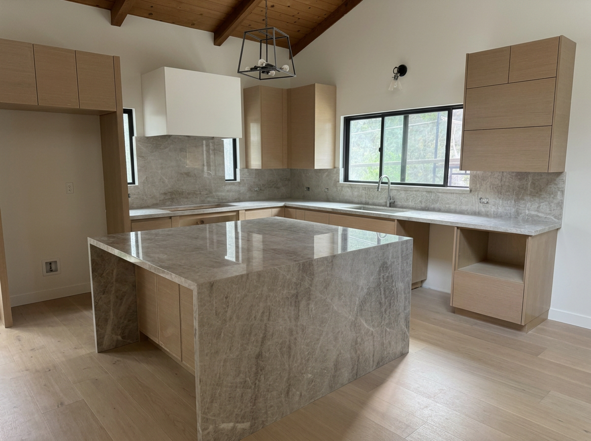 Modern kitchen with light wood cabinetry, marble countertops, an island, a large window, and a wooden ceiling.