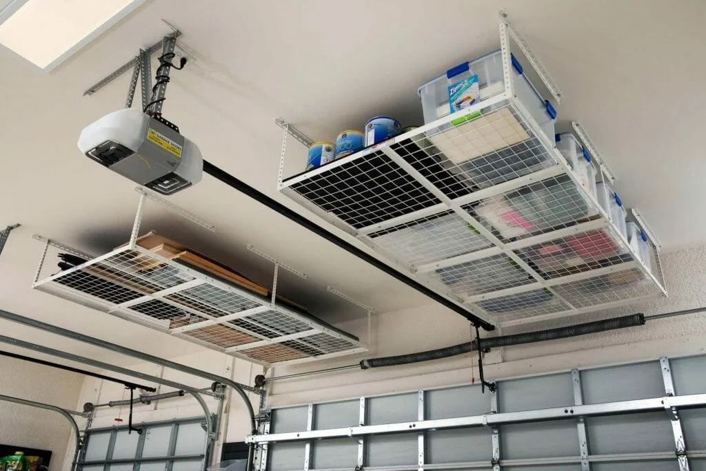 Garage ceiling with overhead storage cages for organization, a garage door, and a mounted garage door opener.