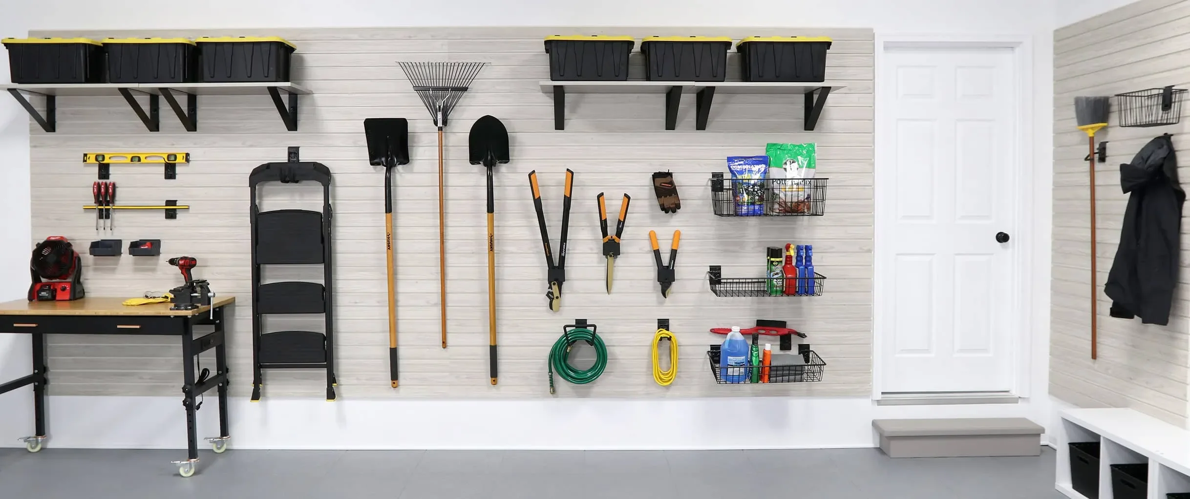 Organized garage wall with storage shelves, tools, gardening equipment, and cleaning supplies.
