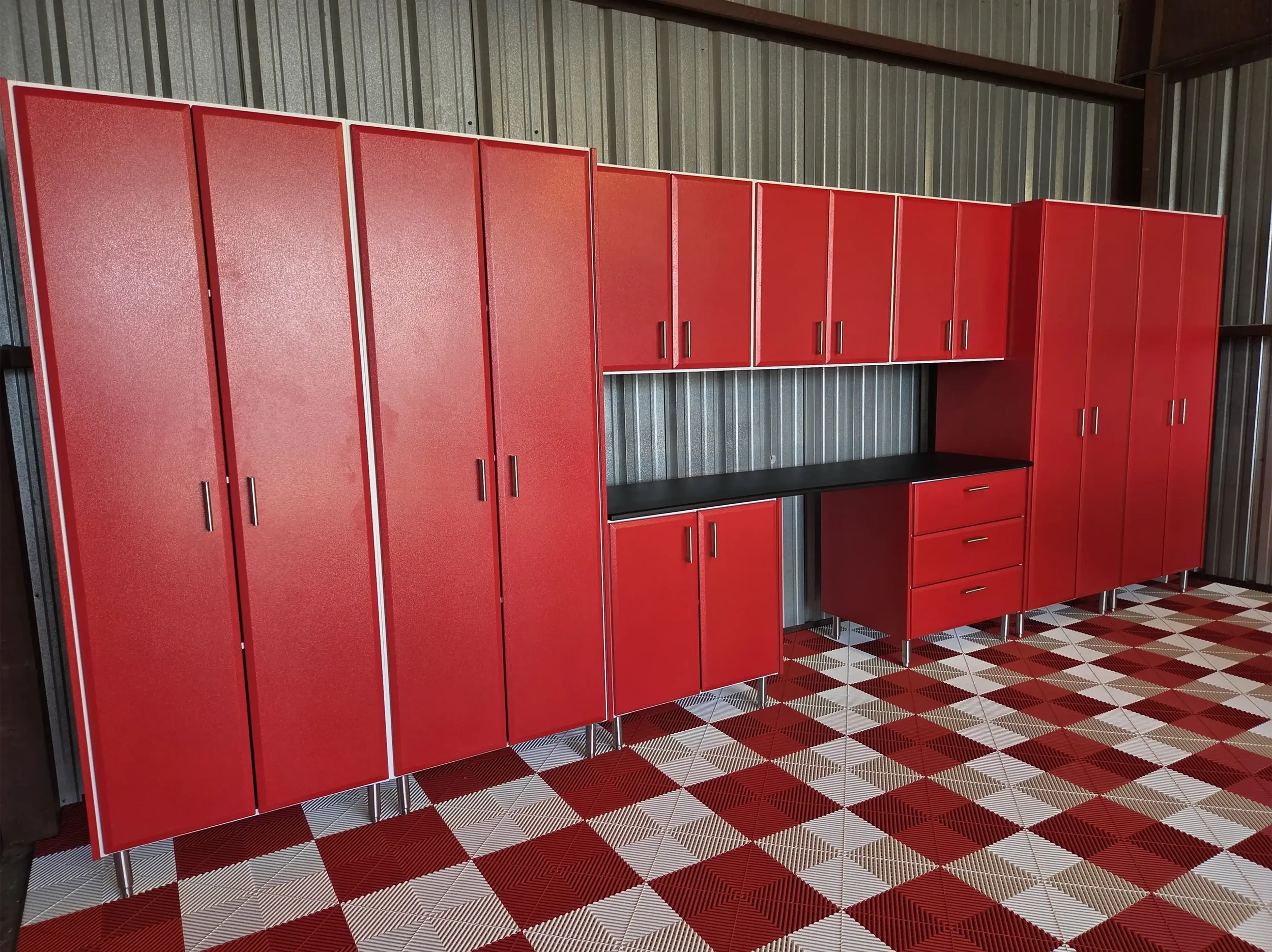 Red metal lockers with black handles and a black countertop, set against a silver corrugated metal wall, on a red, black, and white checkered floor.