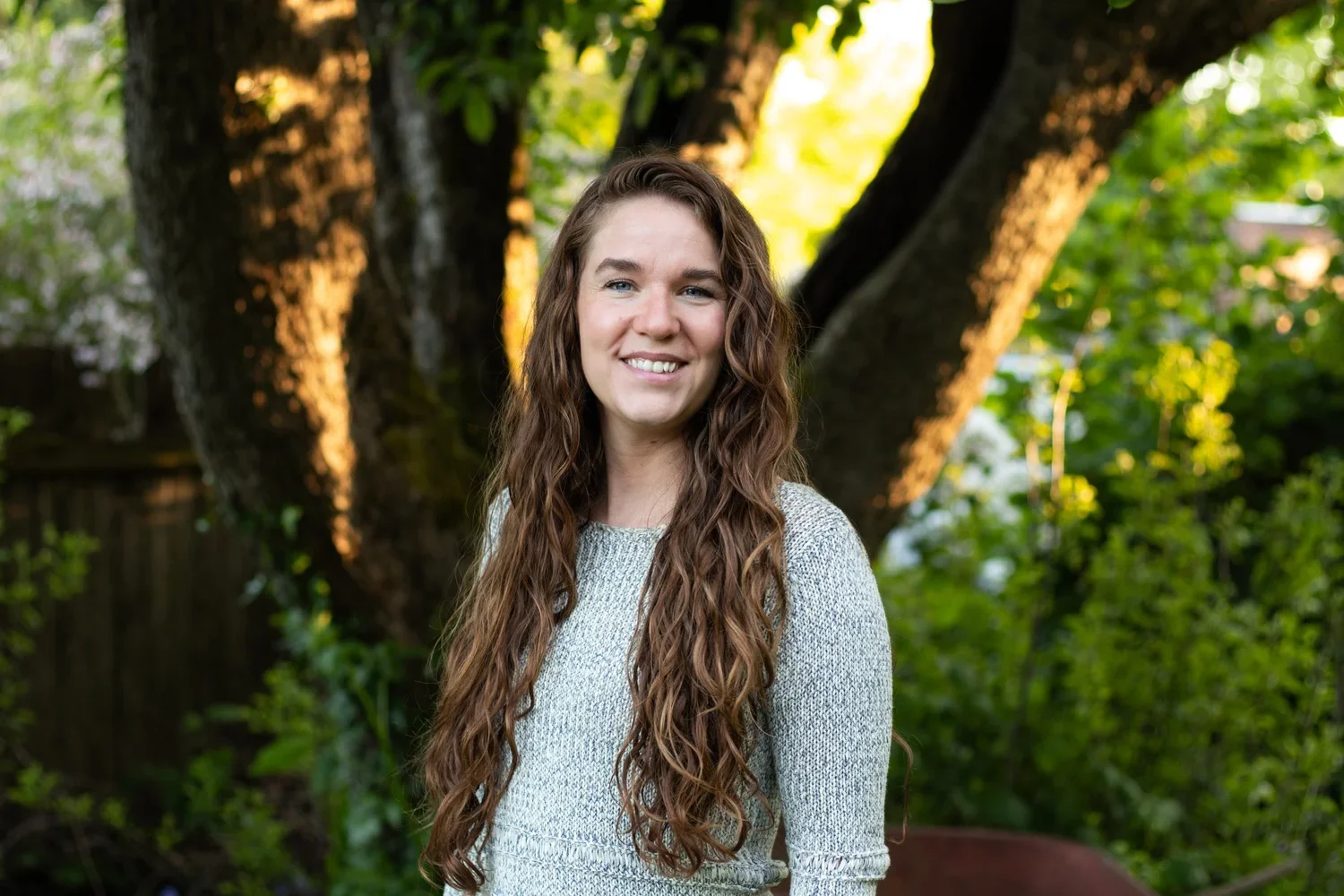 A young woman with long, curly brown hair smiling nutritionist, dietitian, gut microbiome, wellness, inflammation
