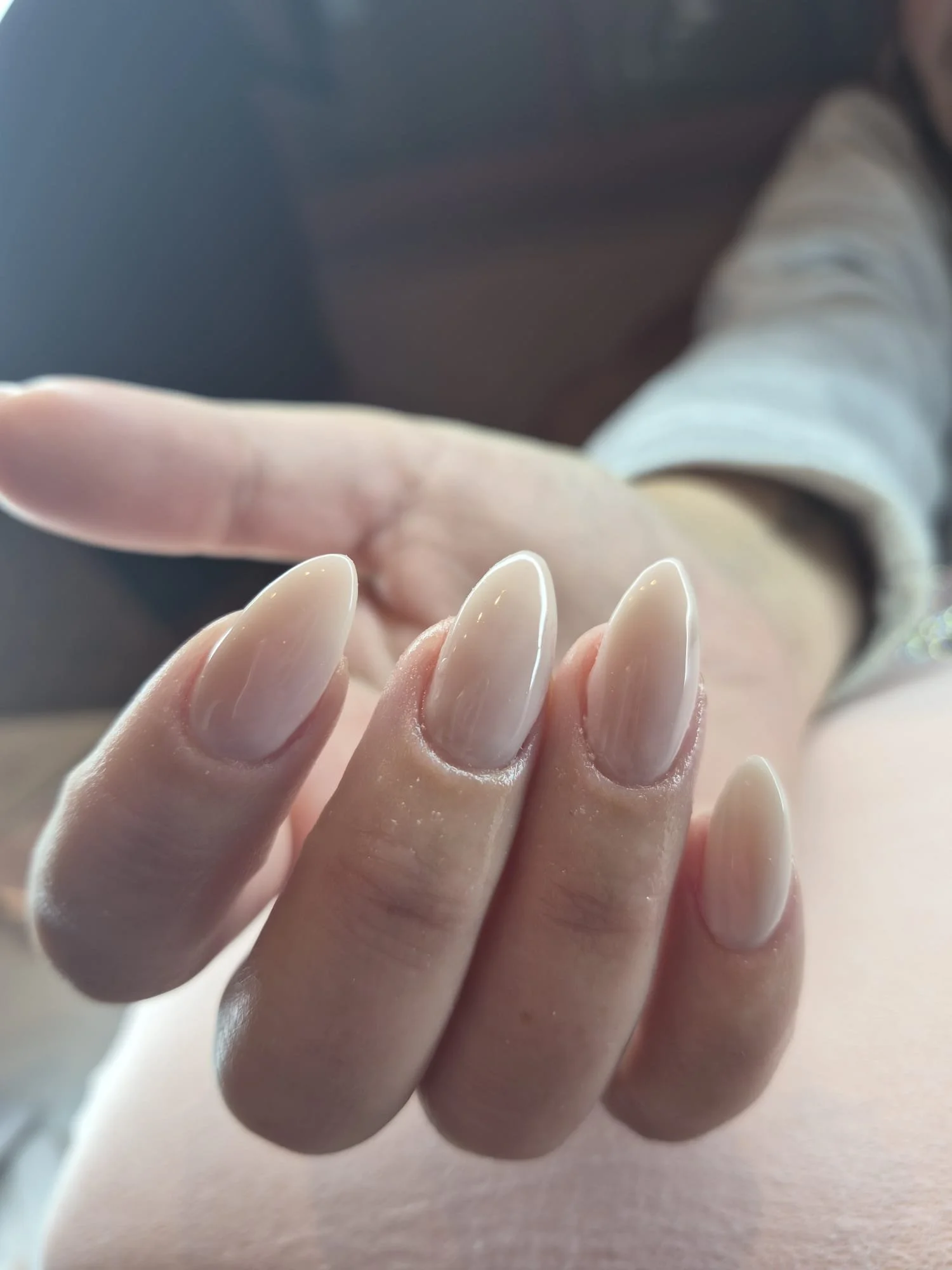 Close-up of a hand with manicured nails, reaching out towards a reflective surface.