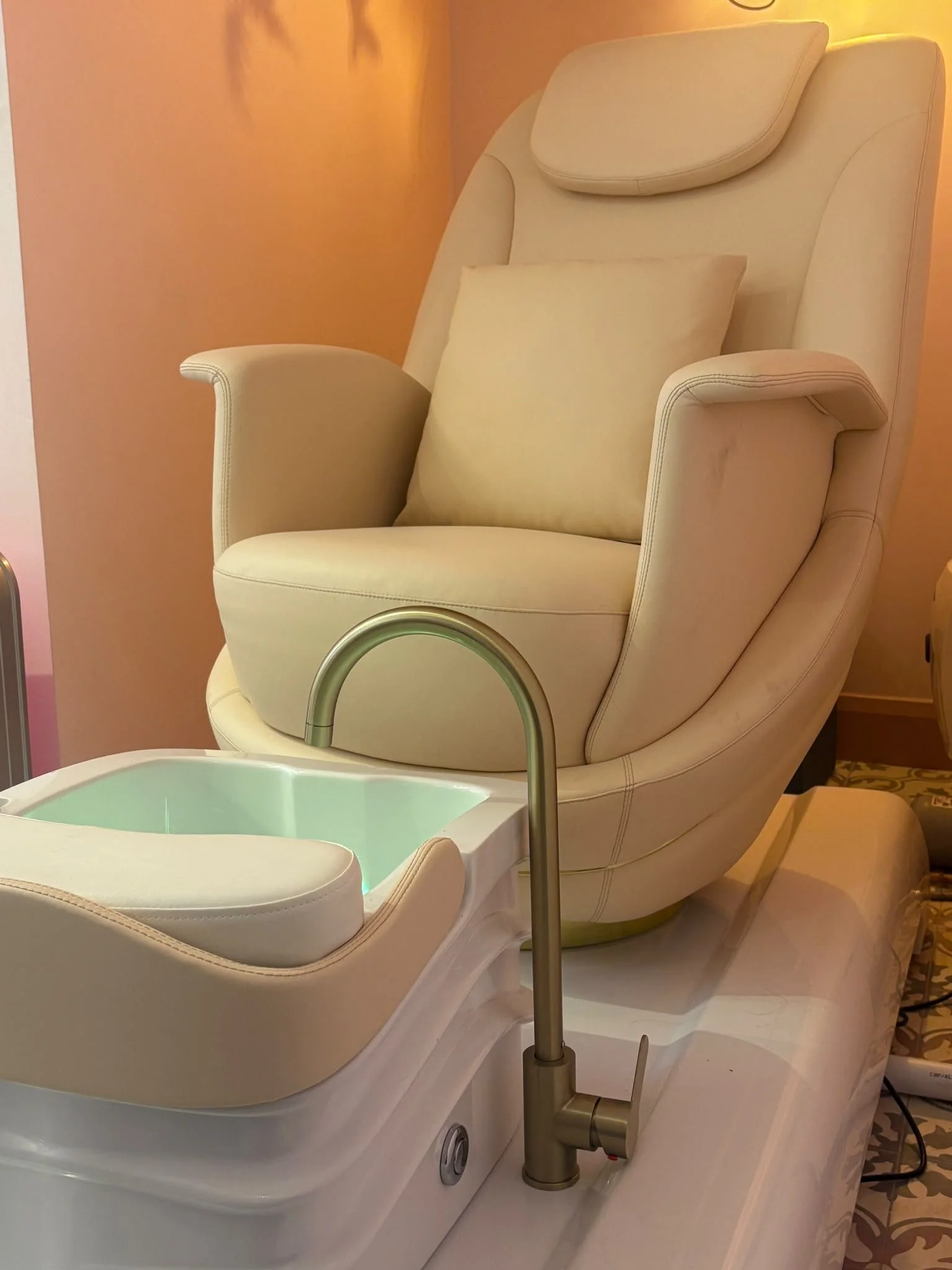 A white themed pod bed with a pillow, a curved headrest, and a water basin in front with soft lighting in a cozy room.
