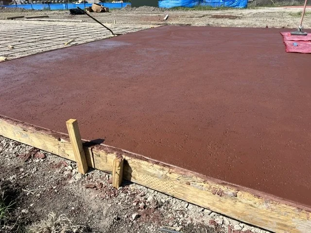 Freshly poured concrete slab with a wooden form around the edges at a construction site.