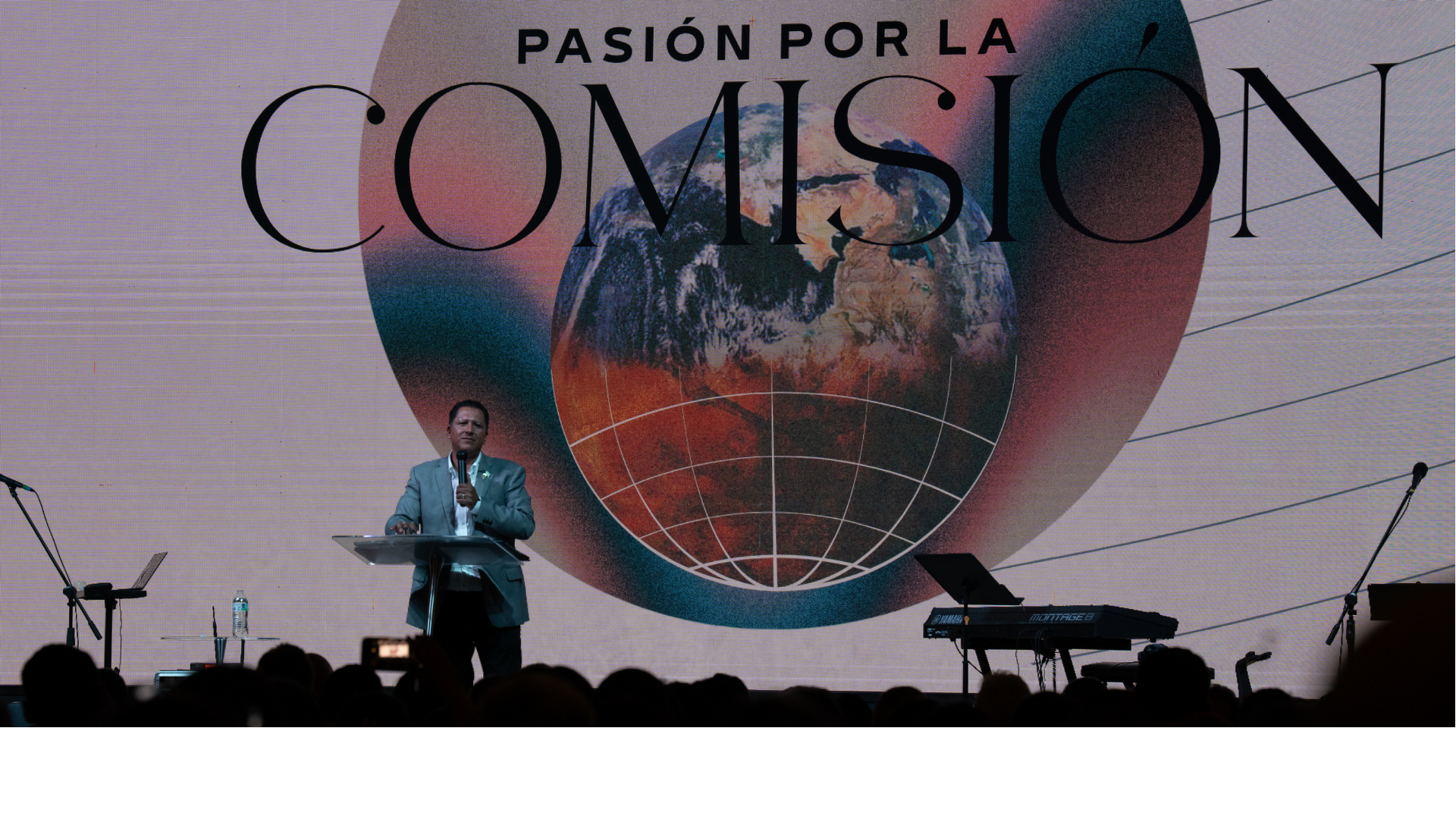 Persona dando un discurso frente a un fondo con un globo terráqueo y la frase "Pasión por la Comunión" en letras grandes.