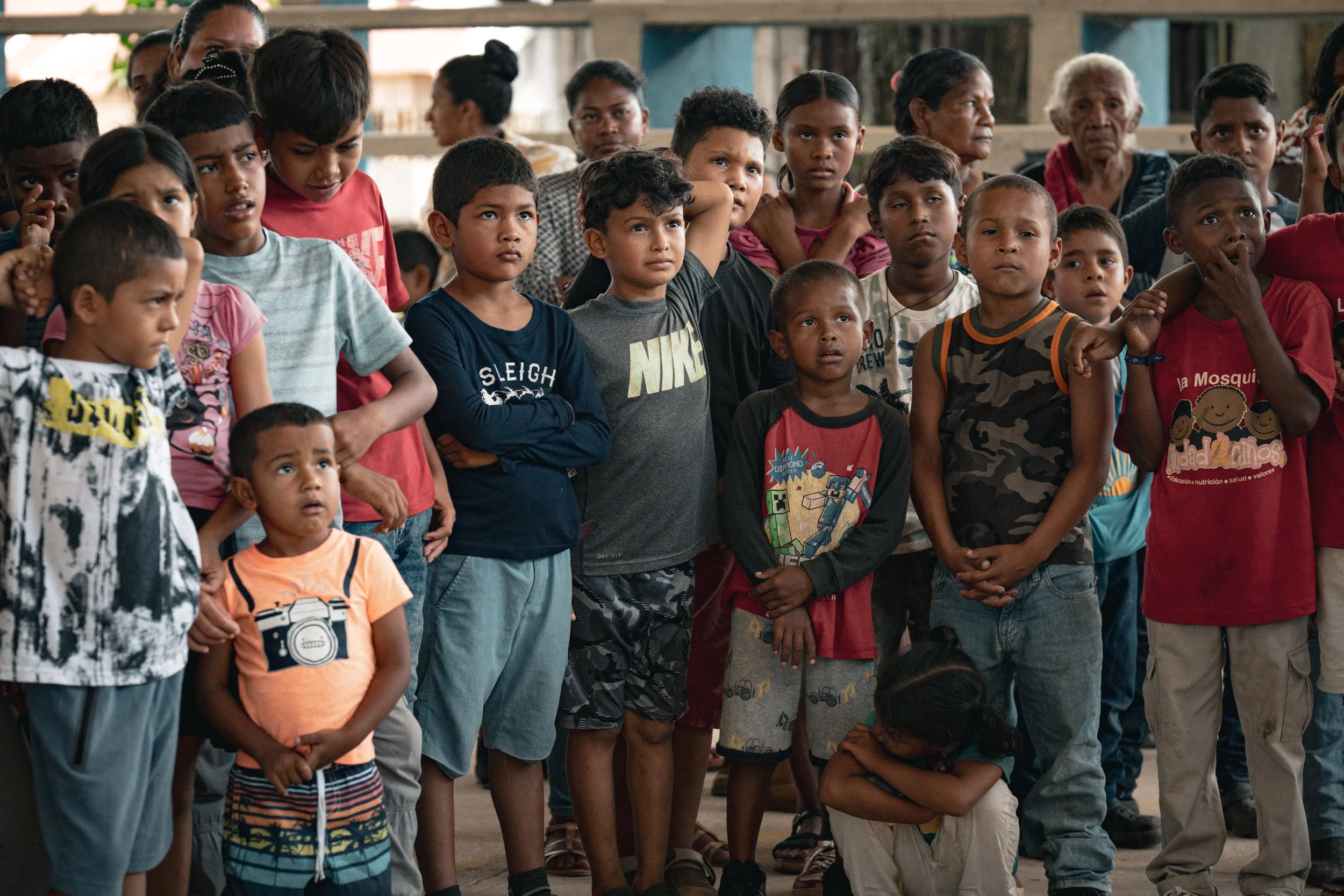 Grupo de niños y niñas de diferentes edades observando con atención. Algunos parecen estar sorprendidos o concentrados, mientras otros muestran expresiones de curiosidad o inquietud.