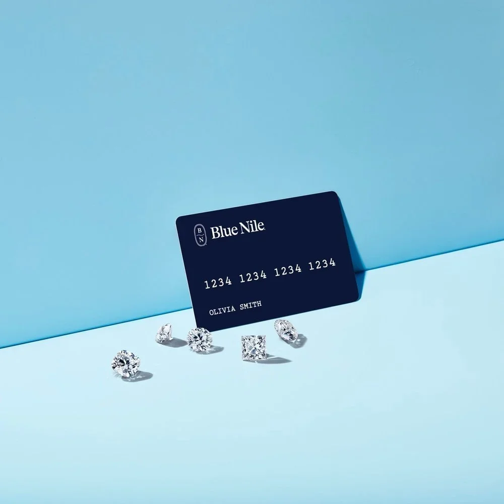 A Black Card with the logo 'Blue Nile' and a placeholder number, along with five diamonds on a light blue background.