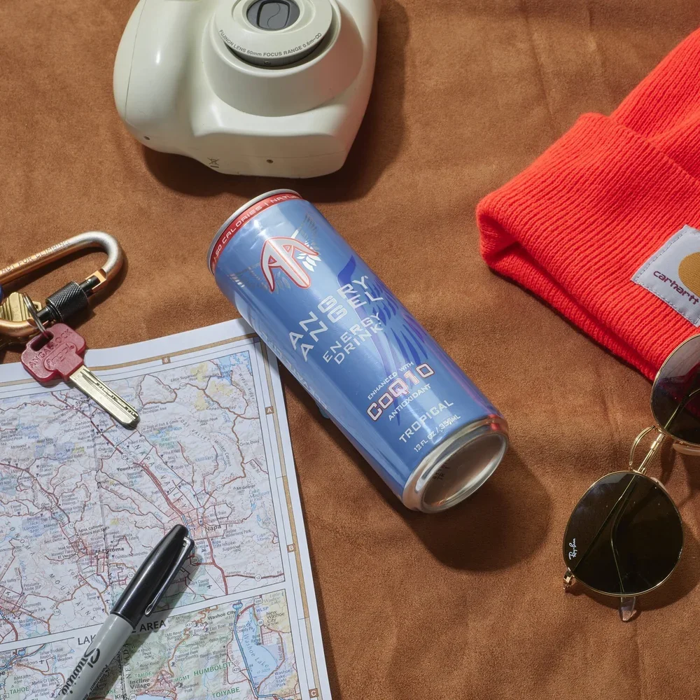 A map of the Lake Tahoe area on a brown surface, with a set of keys, a black Sharpie marker, a blue energy drink can, a white camera, a red beanie, and a pair of Ray-Ban sunglasses.