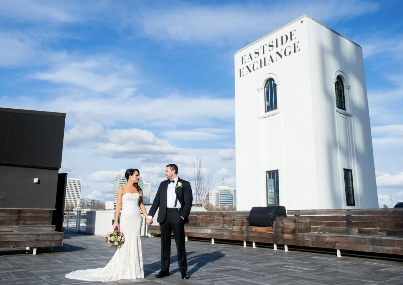 Newlywed couple holding hands on the Cascade Rooftop with Portland views.