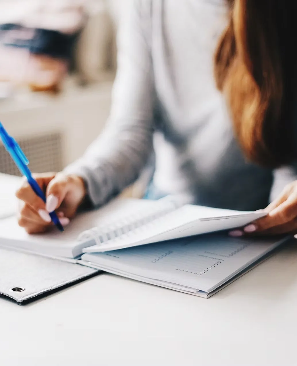 Person writing in a notebook at a desk