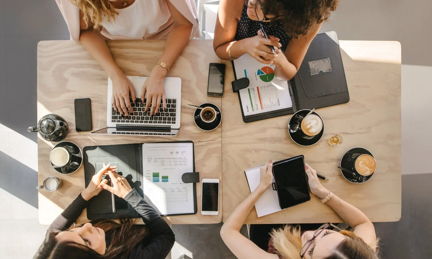 Four people working together at a large wooden desk