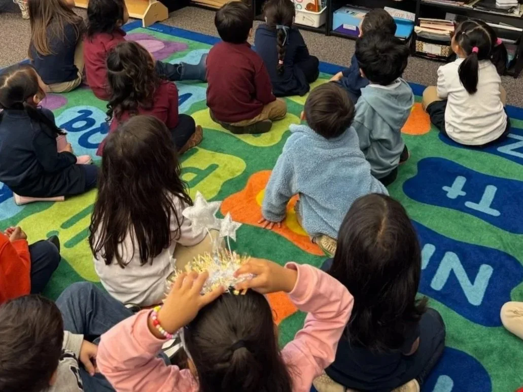 Group of young children sitting on a colorful classroom rug.