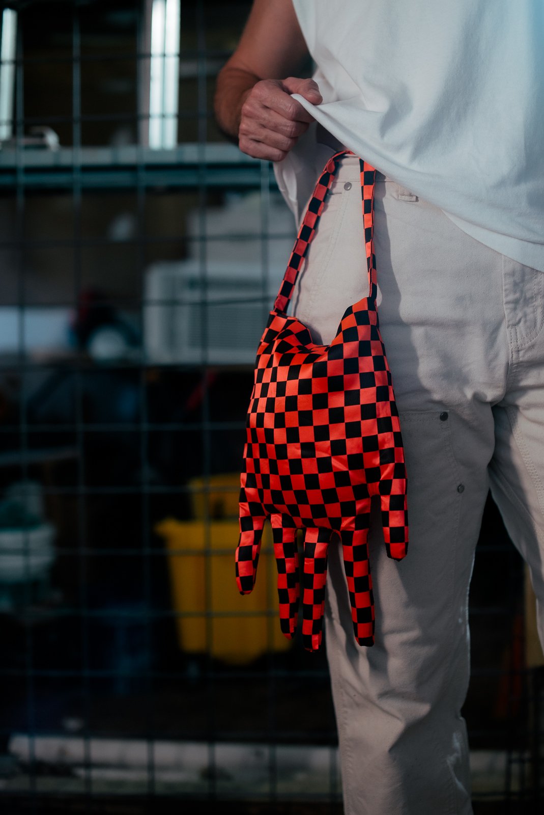 Person in a white shirt holding a red and black checkered glove.