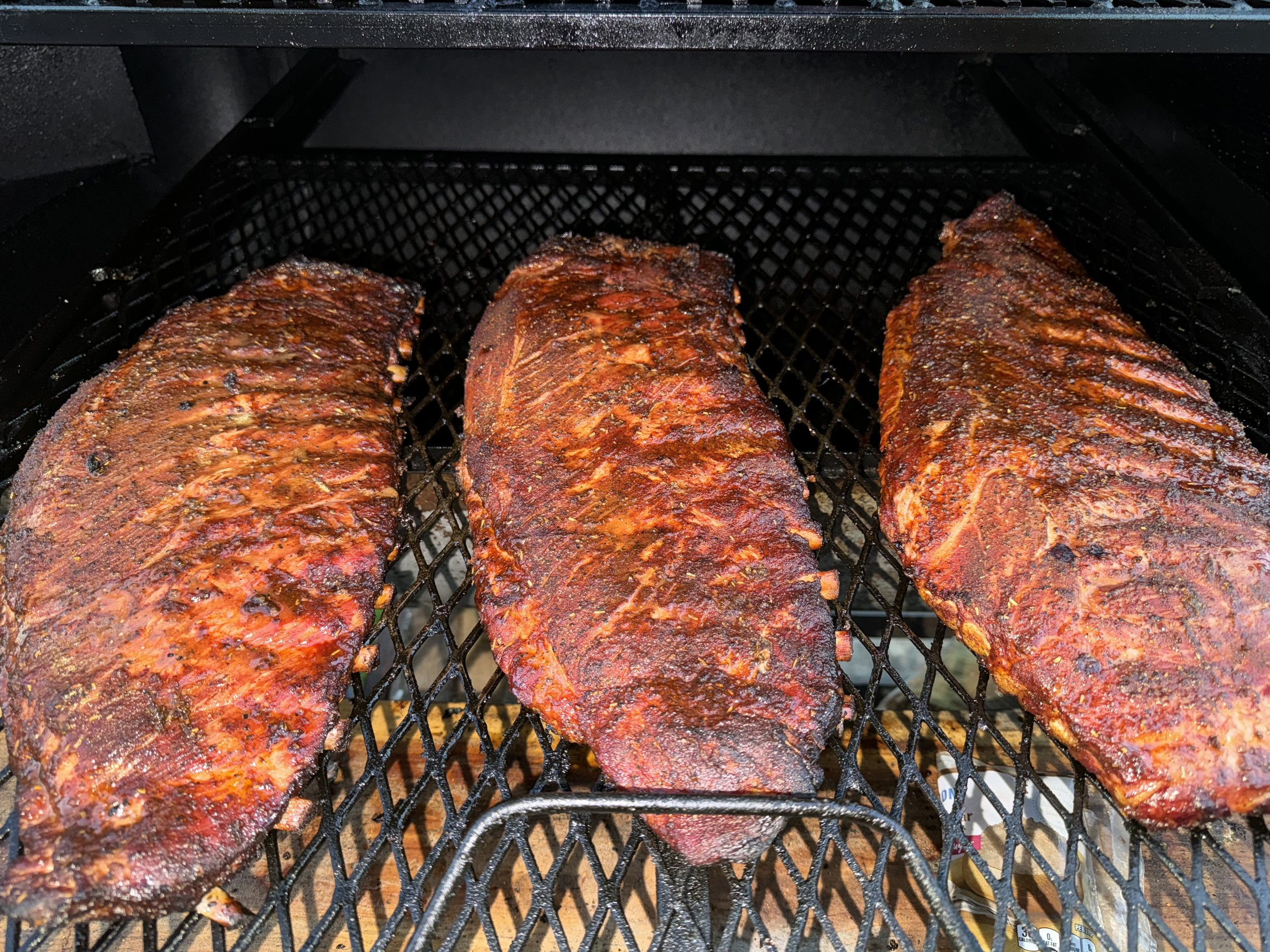 Three racks of seasoned spareribs smoked with love and hickory wood on offset smoker.