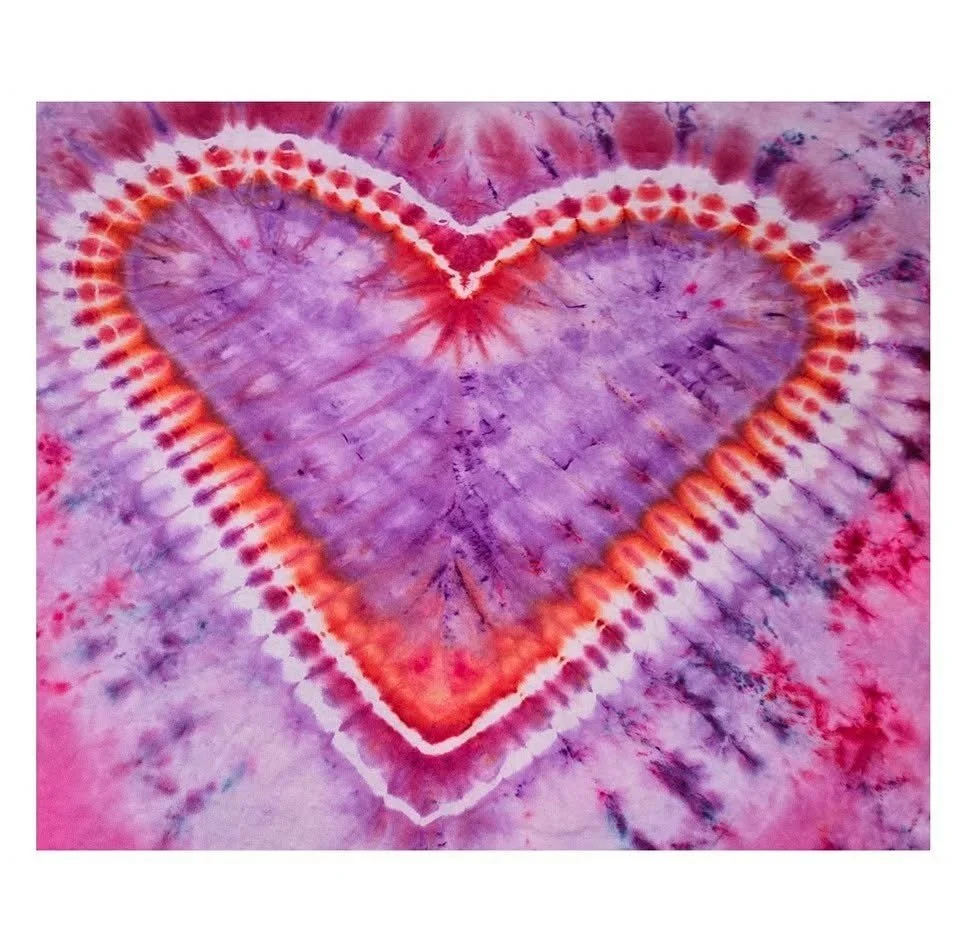 Tie-dye fabric featuring a large heart shape in purple, red, orange, and pink colors.