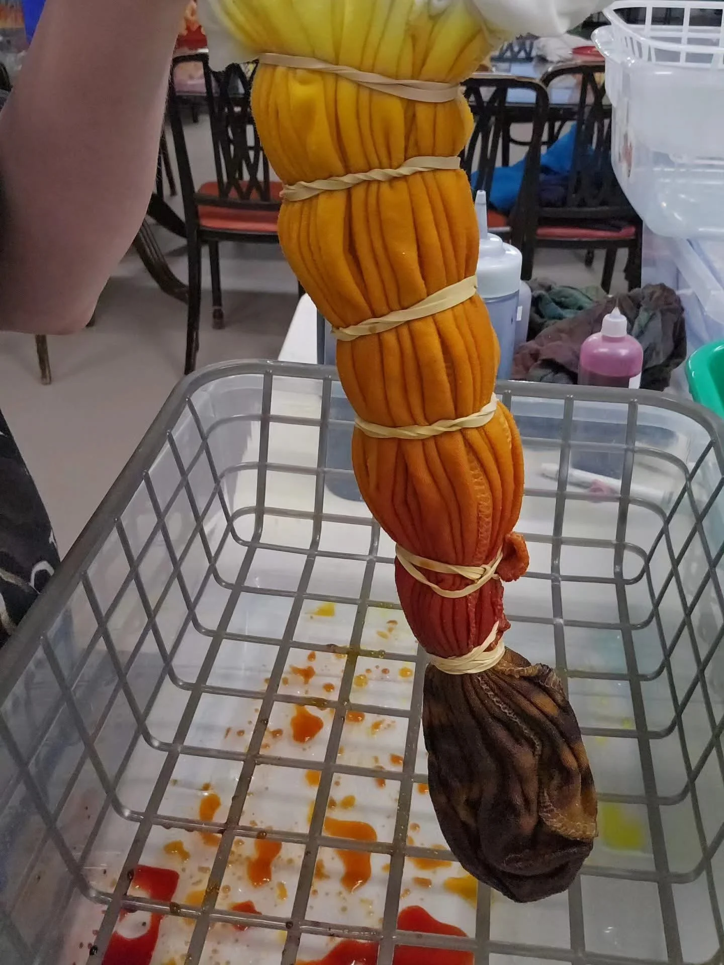 Colorful dried gourds stacked and tied together with rubber bands inside a shopping basket, with some orange liquid spilled at the bottom.