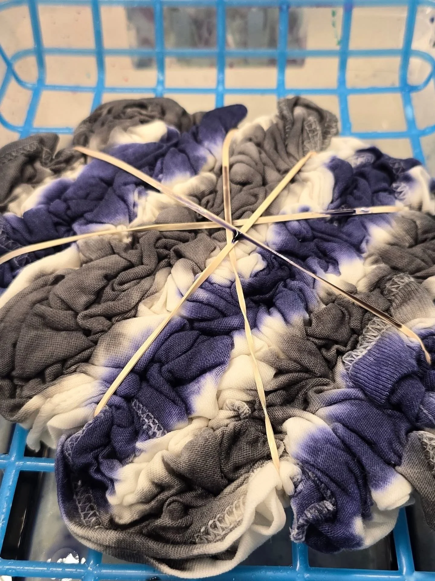 A blue laundry basket filled with tangled, assorted gray and white socks.