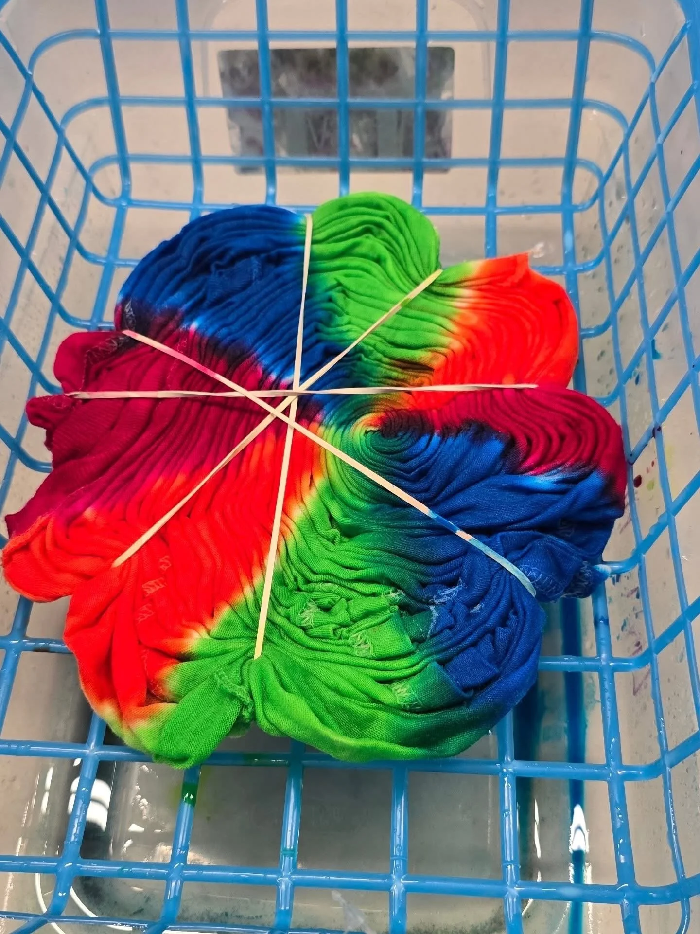 Colorful tie-dye T-shirt with rainbow pattern inside a blue shopping cart.