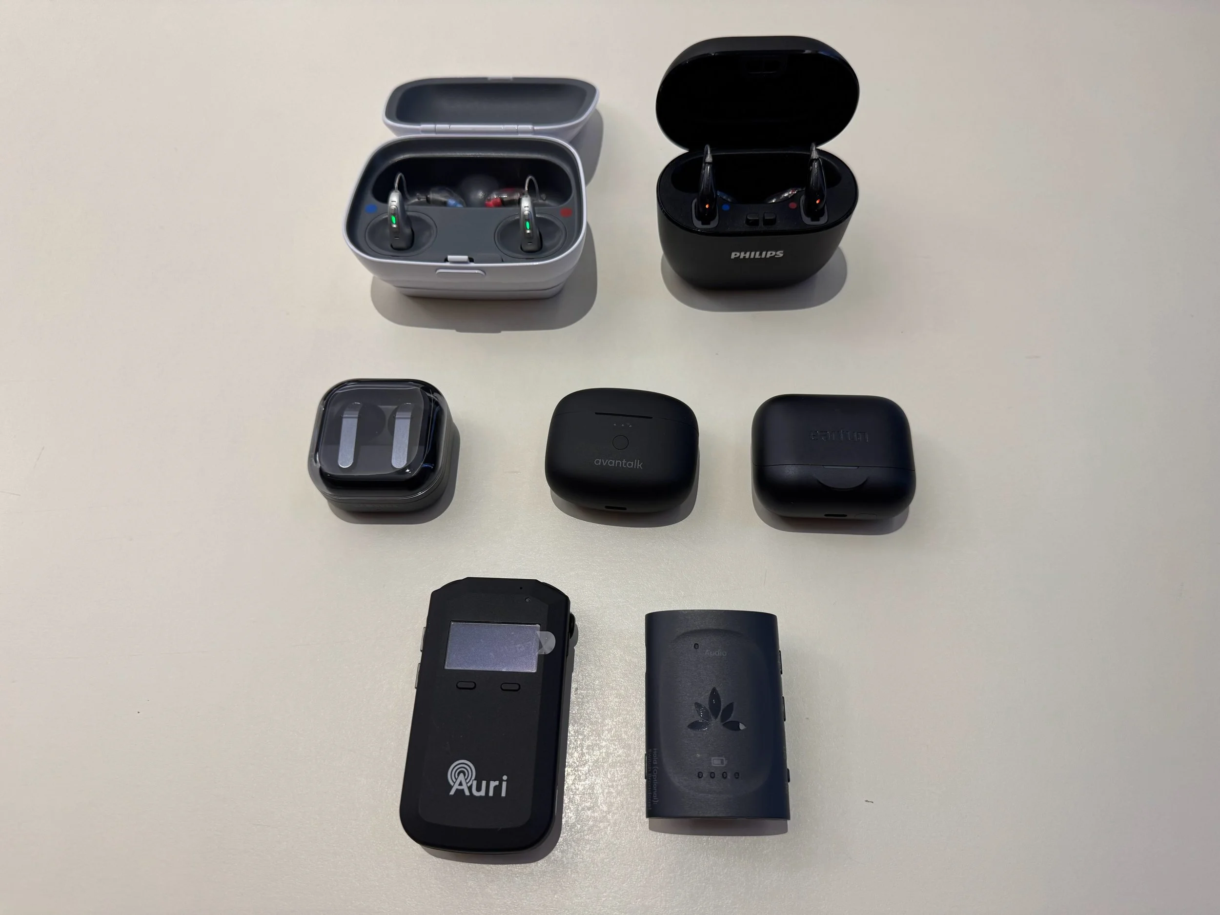 Collection of wireless earbuds and their charging cases on a white surface.