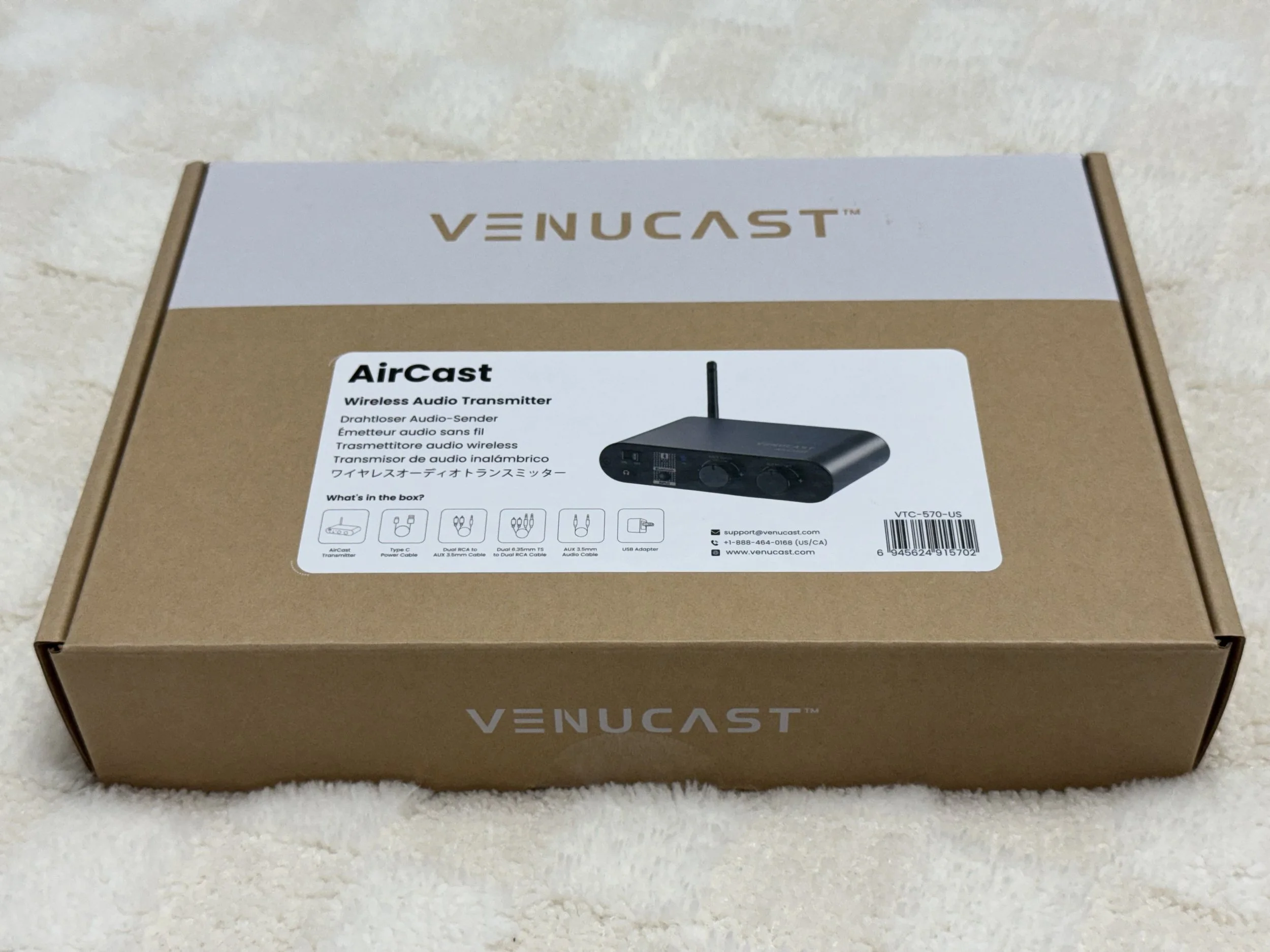 The image shows a box for a Venucast AirCast wireless audio transmitter on a beige surface.