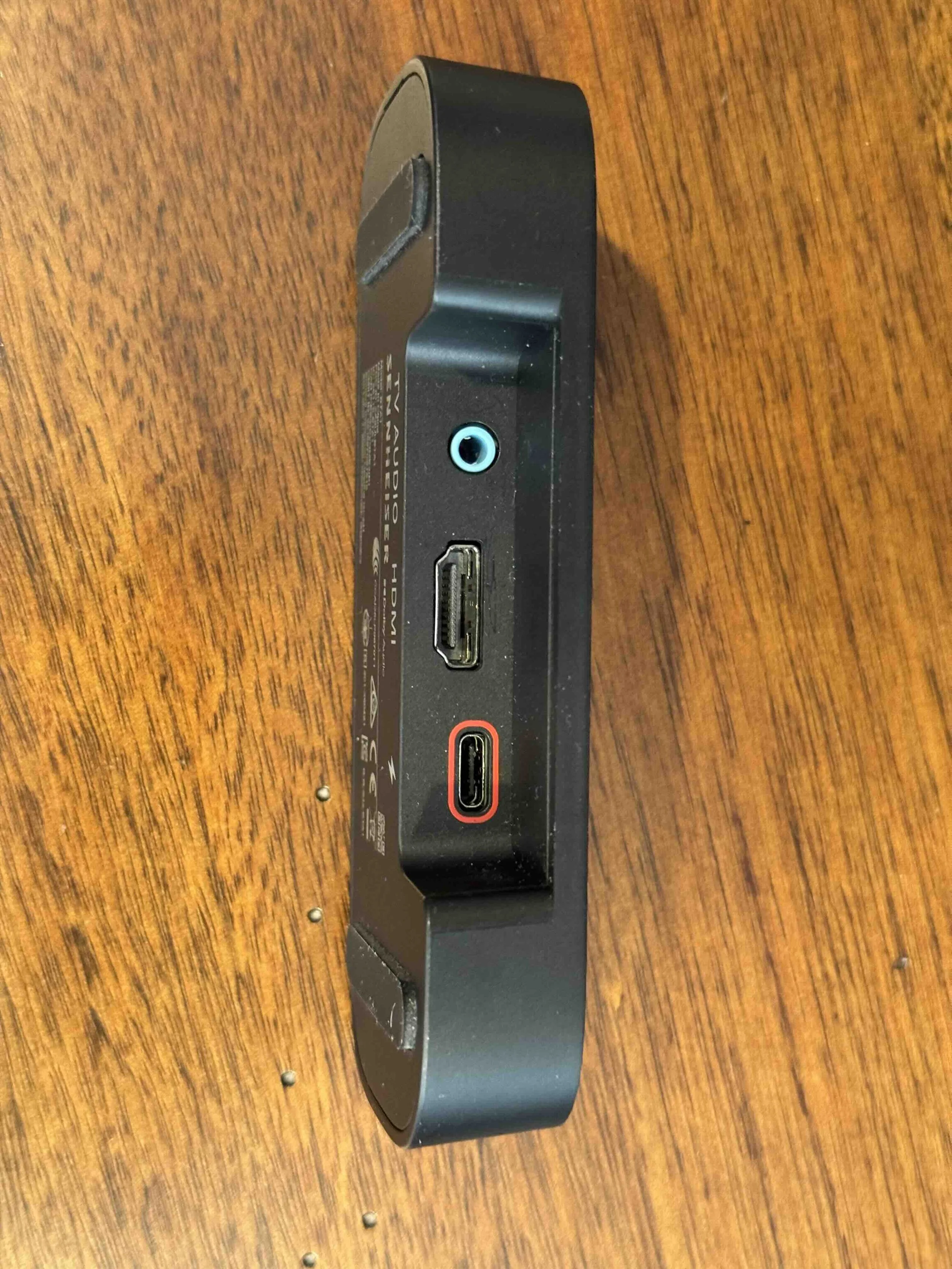 A black electronic device with HDMI and other ports on a wooden surface.