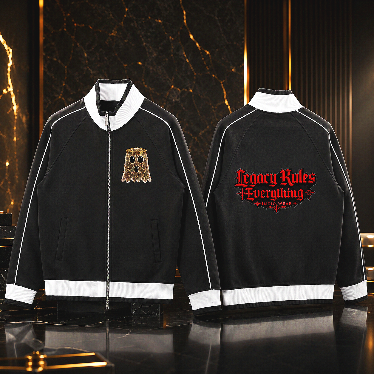 Two black jackets with white trim displayed in a luxury setting, one with a gold embroidered alien head patch on the chest and the other with red embroidered text on the back that reads 'Legacy Rules Everything - Indio Wear'.