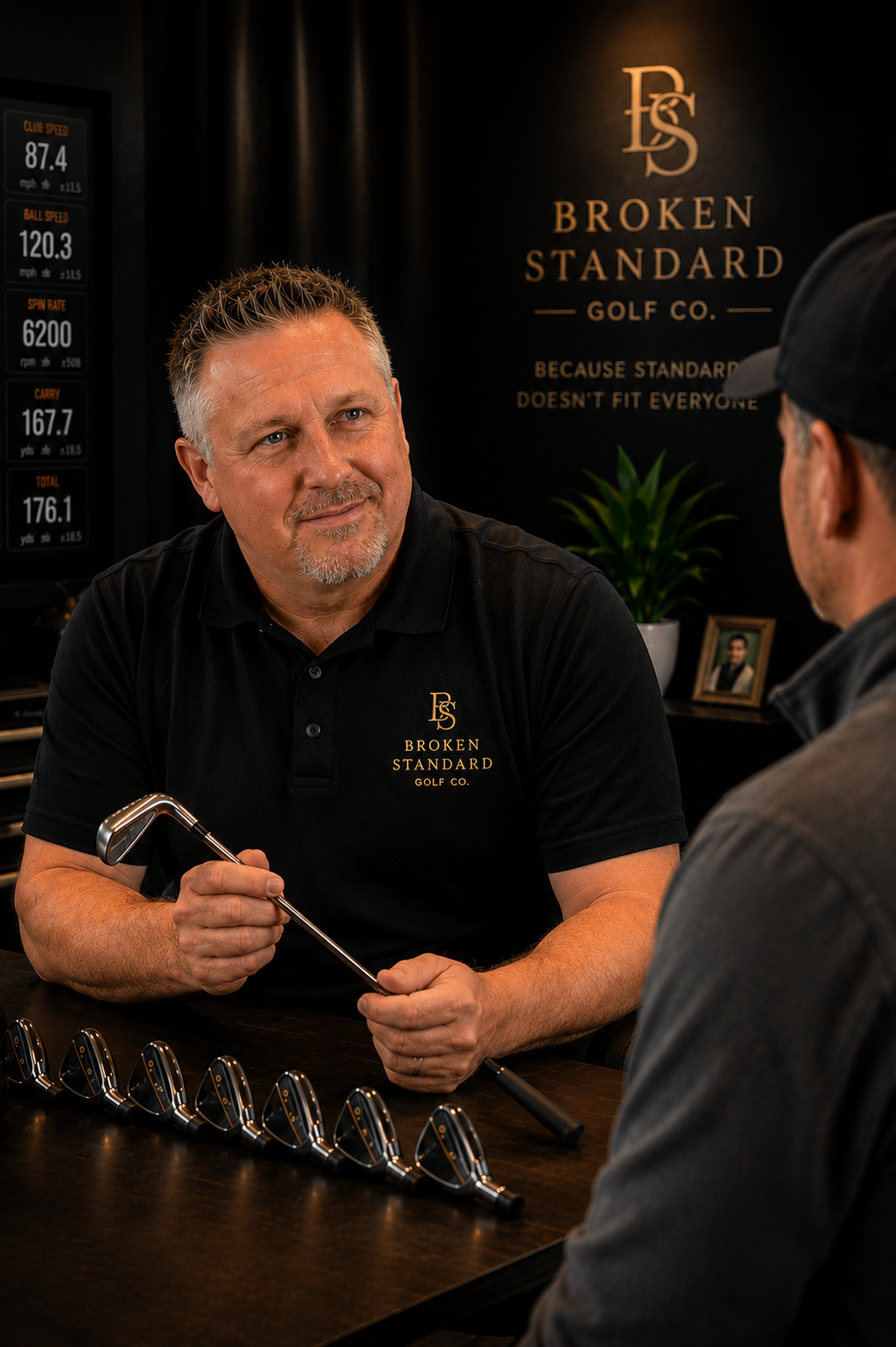Golf fitter discussing an iron with a golfer during a custom club fitting.