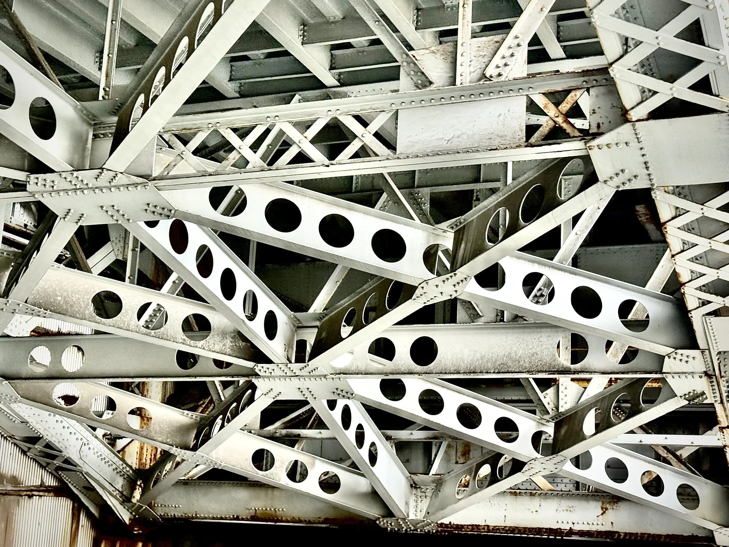 Riveted steel support beams with rows of circular cutouts — industrial circles that inspire Susan Brady's art