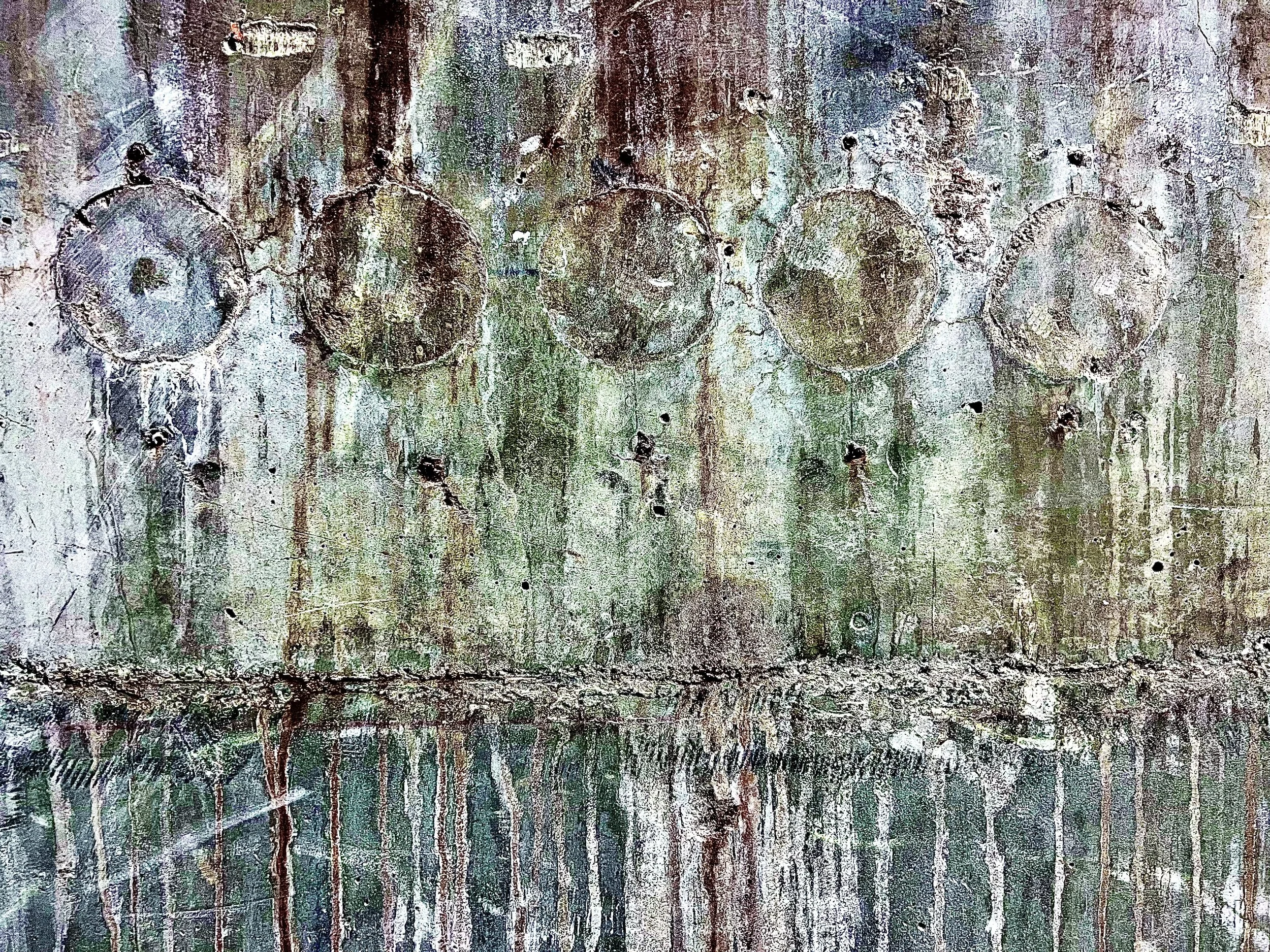 Weathered concrete wall with faint circular marks and streaks of green, purple and rust-colored stains