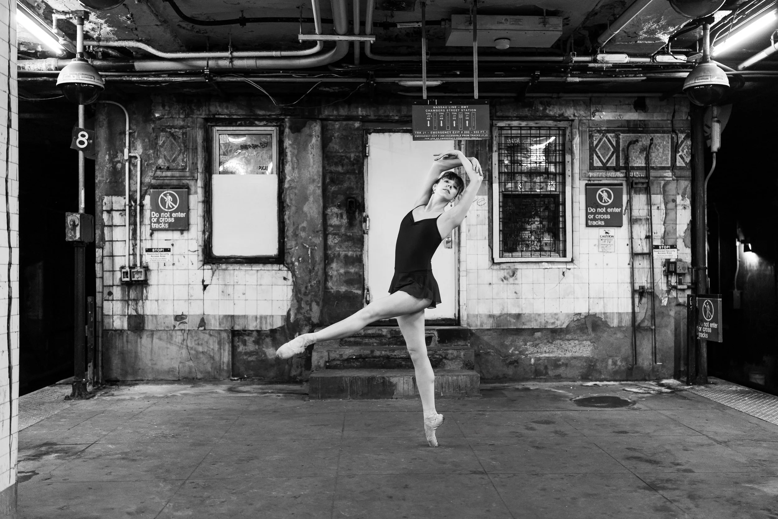 Tori Hey appears in a black-and-white photo performing a ballet pose in an NYC subway station.