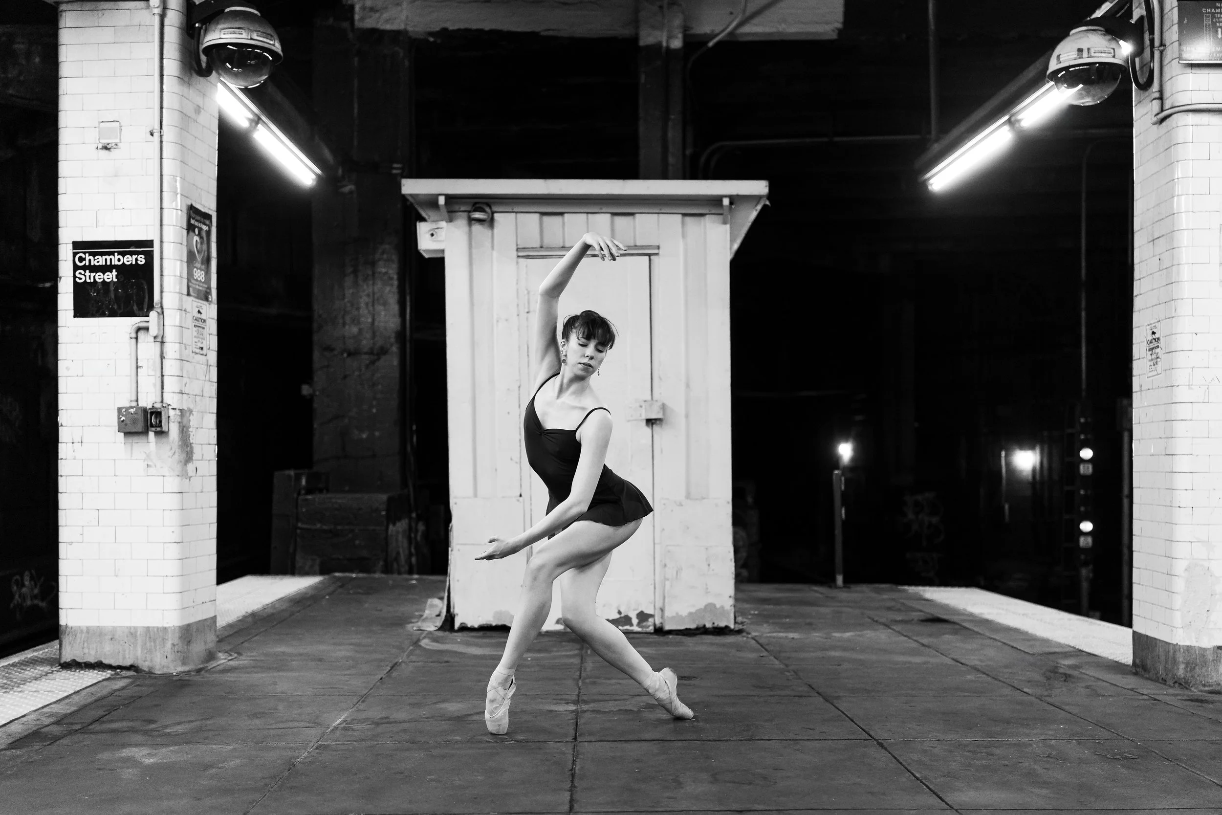 Tori Hey appears in a black-and-white photo performing a ballet pose in an NYC subway station.