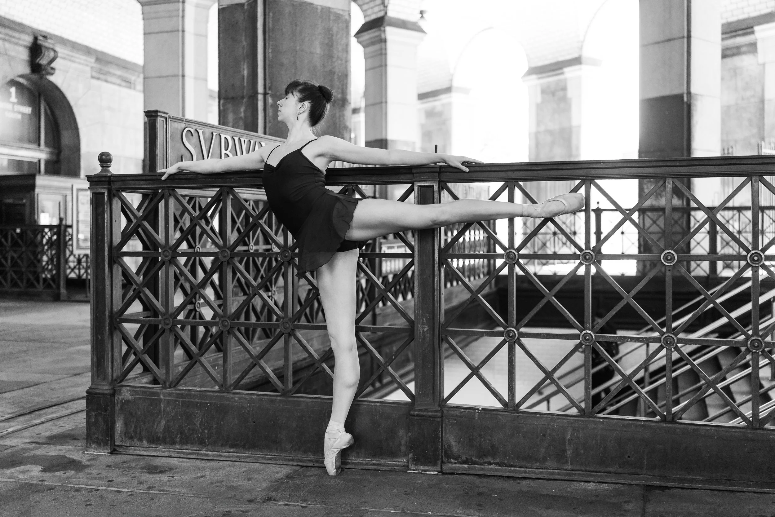 Tori Hey appears in a black-and-white photo performing a ballet pose in an NYC subway station.
