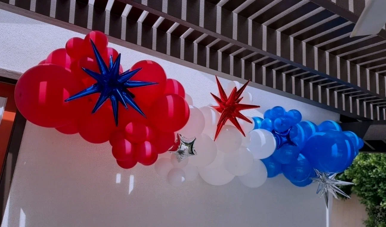 Decorative balloon arrangement with red, white, and blue balloons and star-shaped balloons in matching colors.