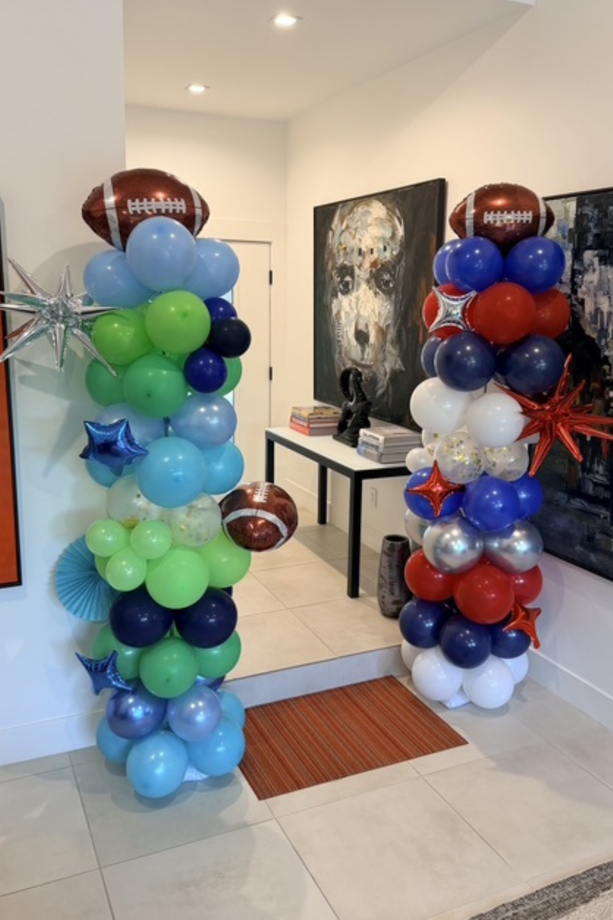 Decorative balloon columns with football-shaped balloons, stars, and various colored round balloons in a house entrance.