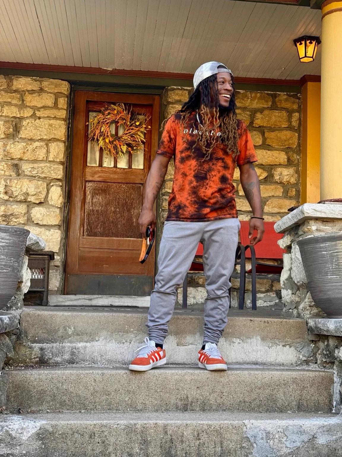 Full length lifestyle portrait in an orange outfit on a porch.