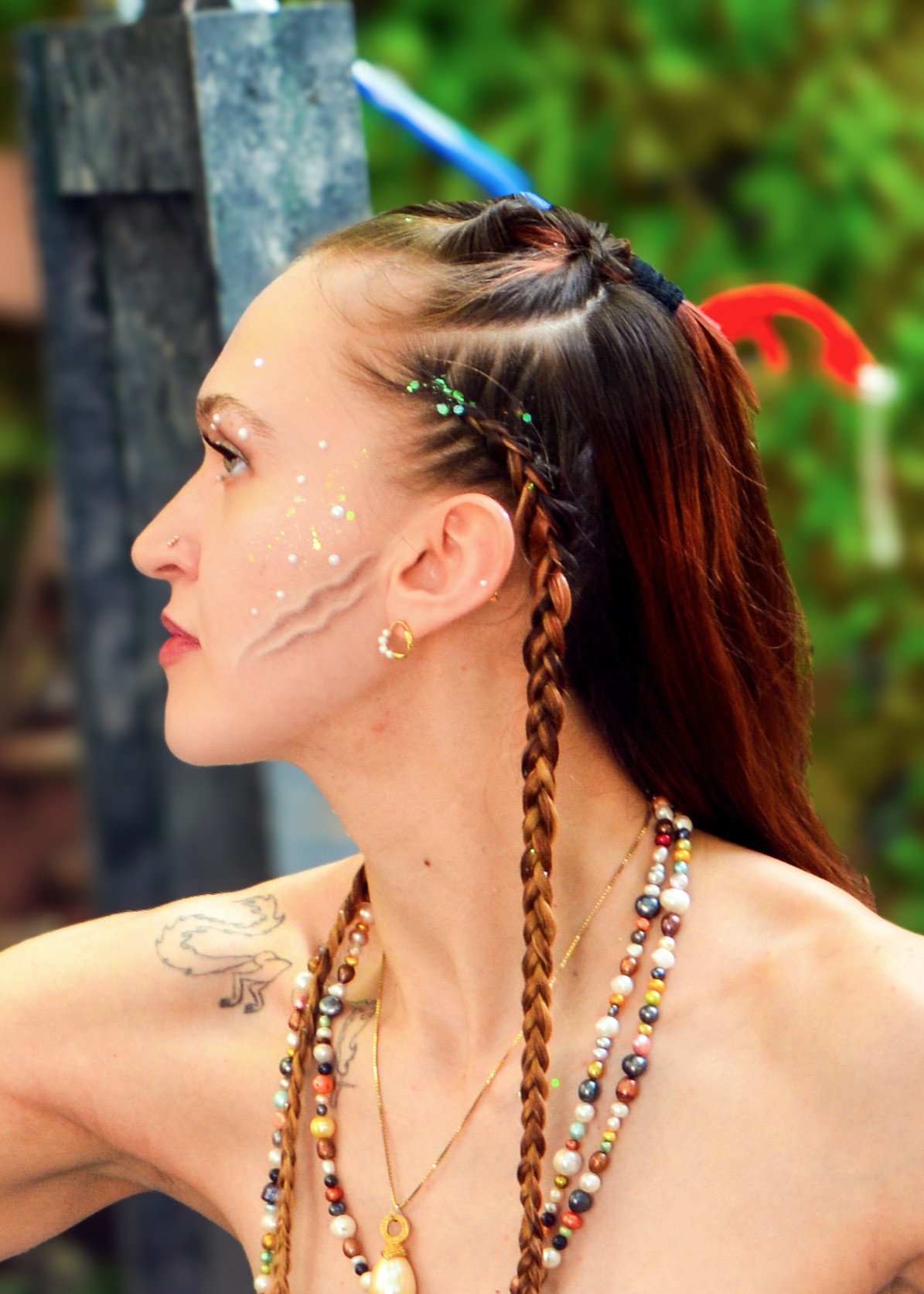 Creative side-profile portrait with decorative makeup and braids.