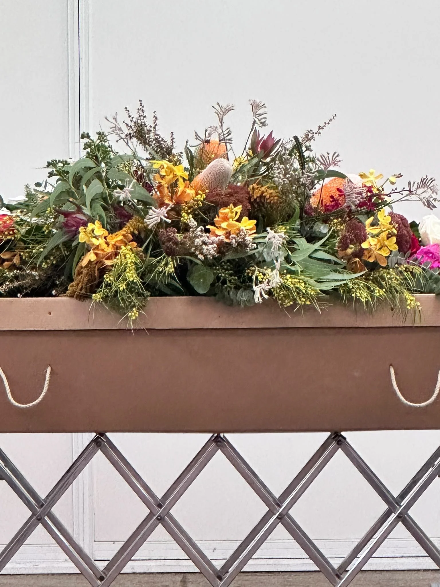 A floral arrangement of Australian natives on a cardboard coffin at a personalised funeral in Sydney
